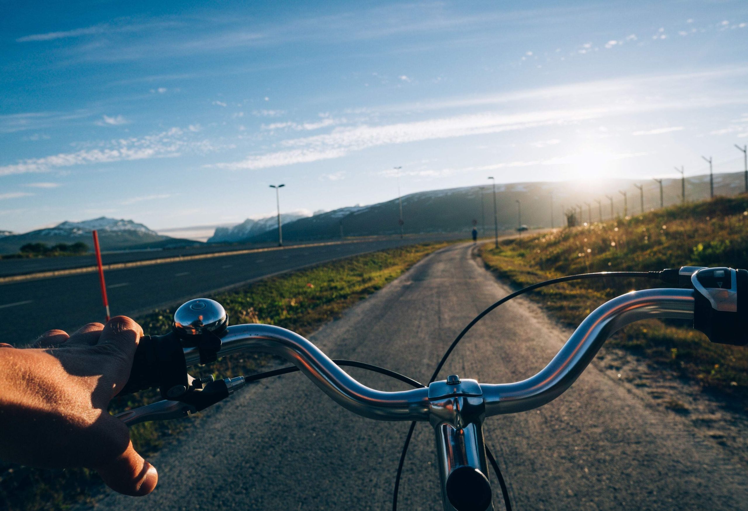 A biker travels on the cycle lane along the broad highway on a sunny day. 