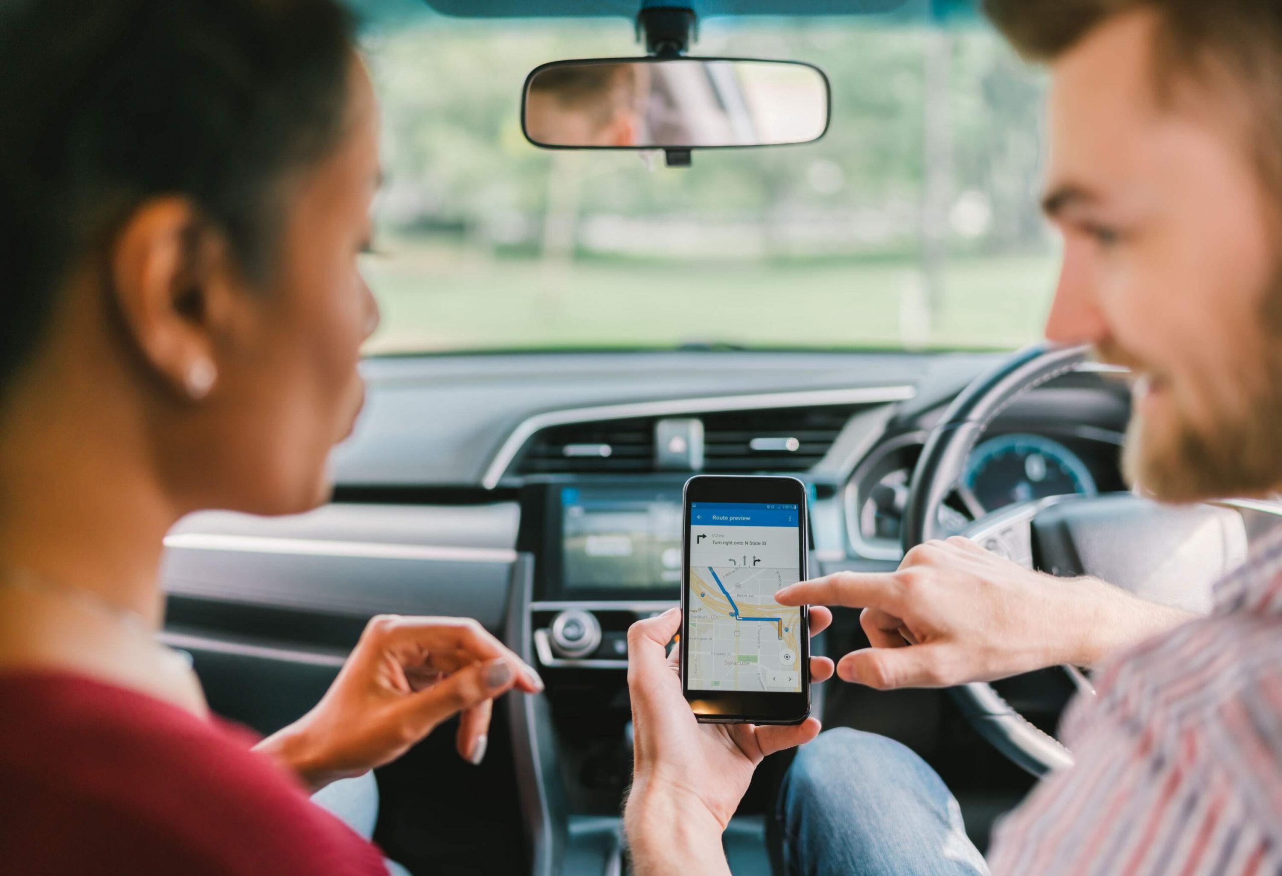 Driver showing his passenger the navigation app on his smartphone.