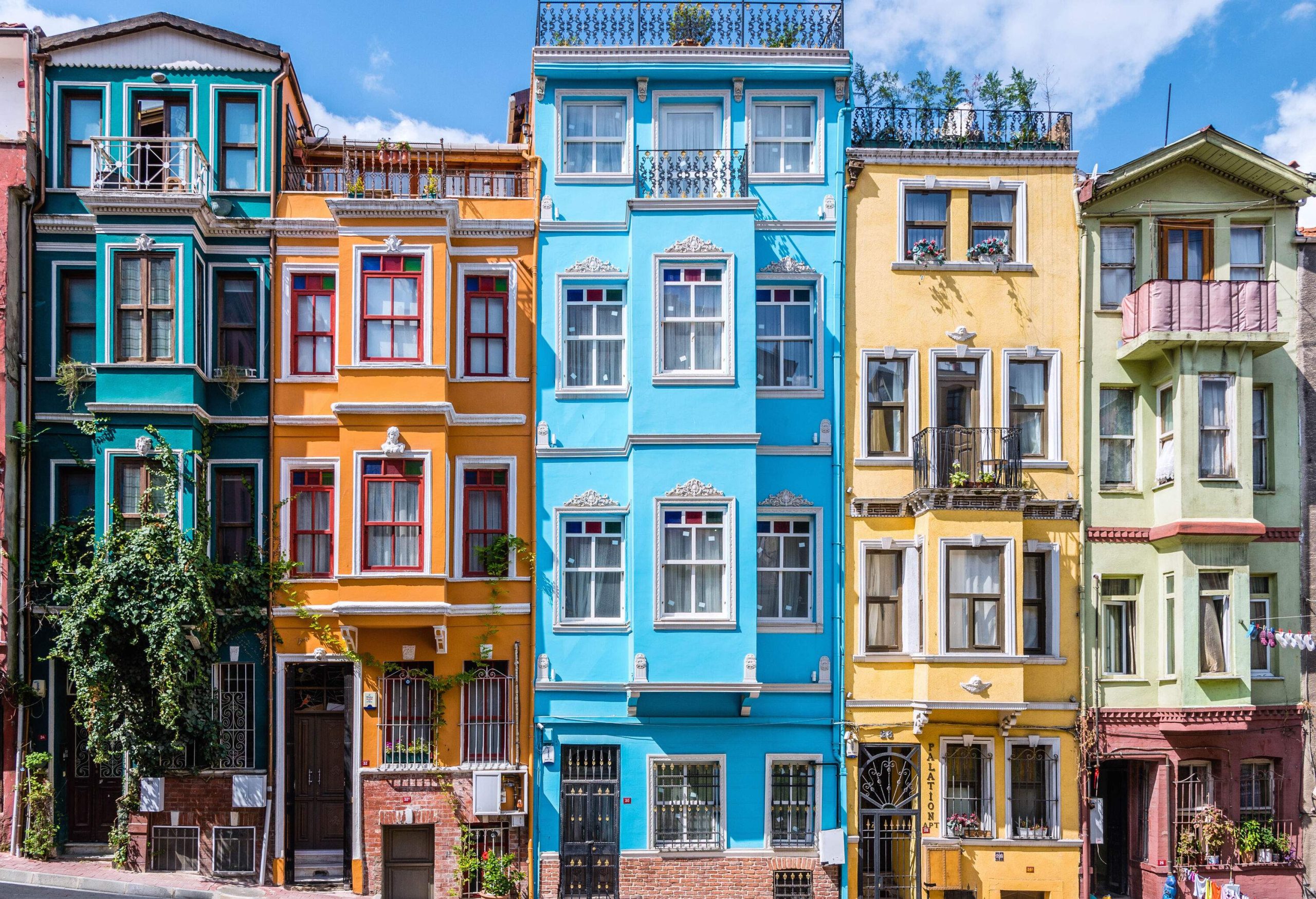 A row of elegant, colourful and classic townhouses with rooftops and balconies.