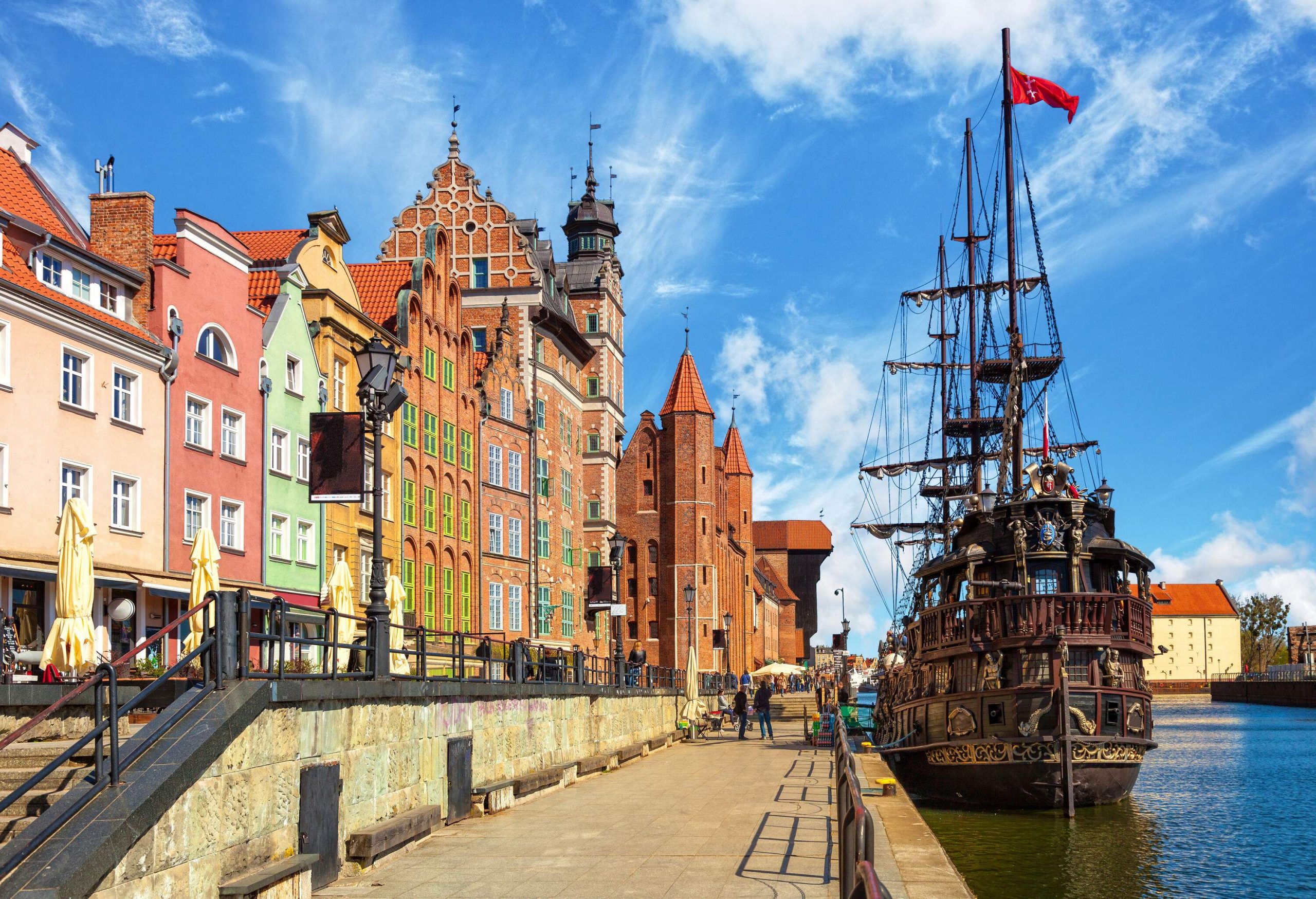 Colourful canalside buildings overlooking a docked Viking ship.