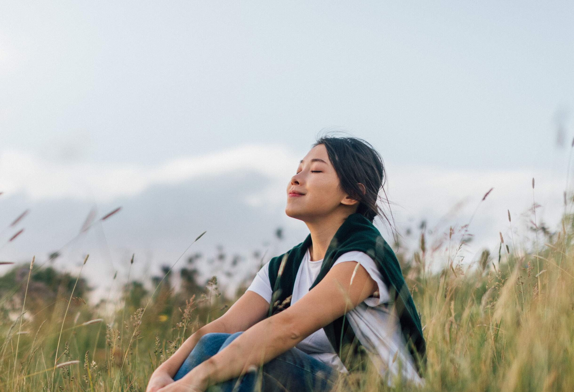 Beautiful young woman removing protective face mask, relaxing at the park to reconnect wit nature after passing Covid-19.