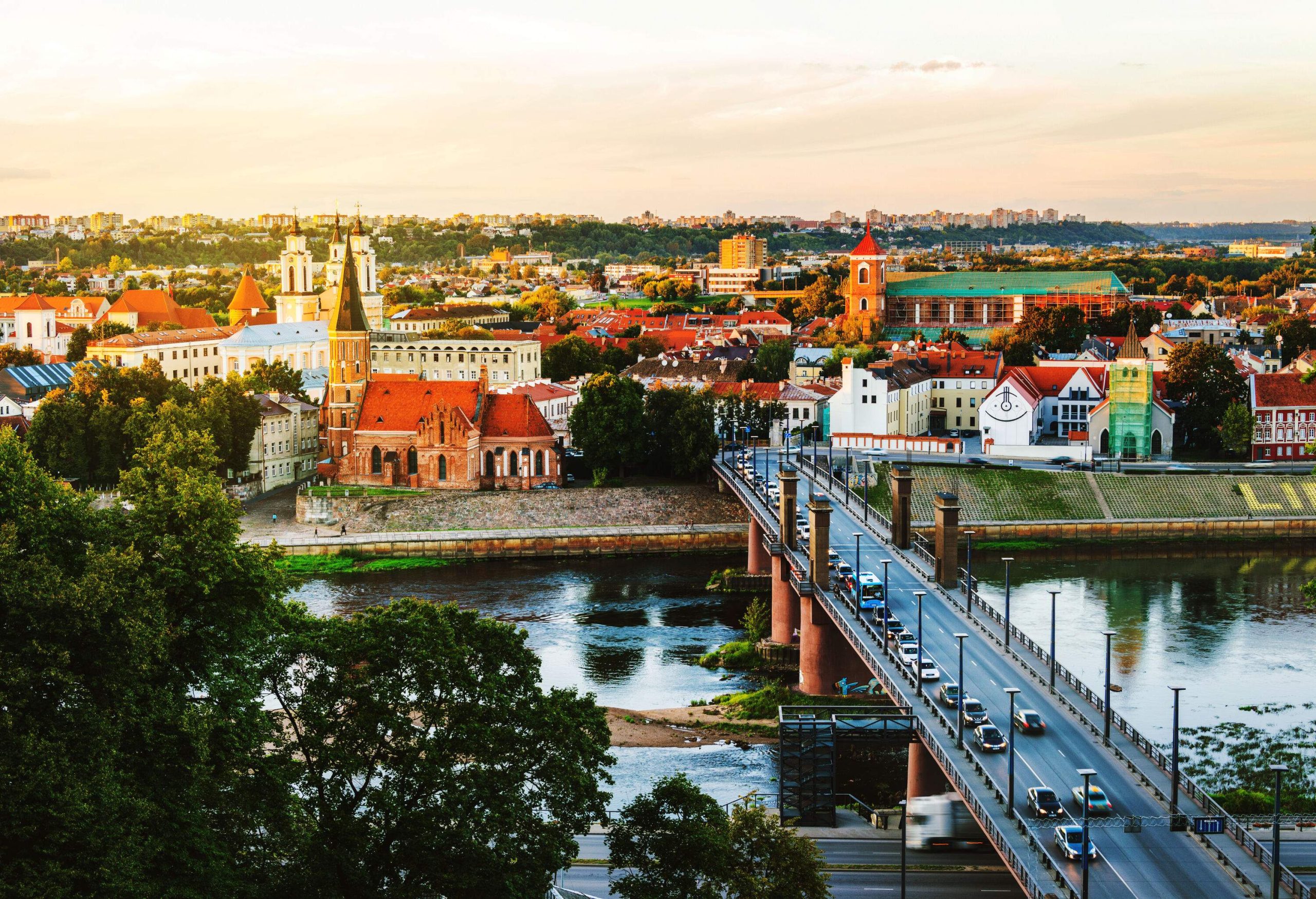 A car gracefully traverses the bridge spanning over the tranquil river, flanked by buildings on both sides.