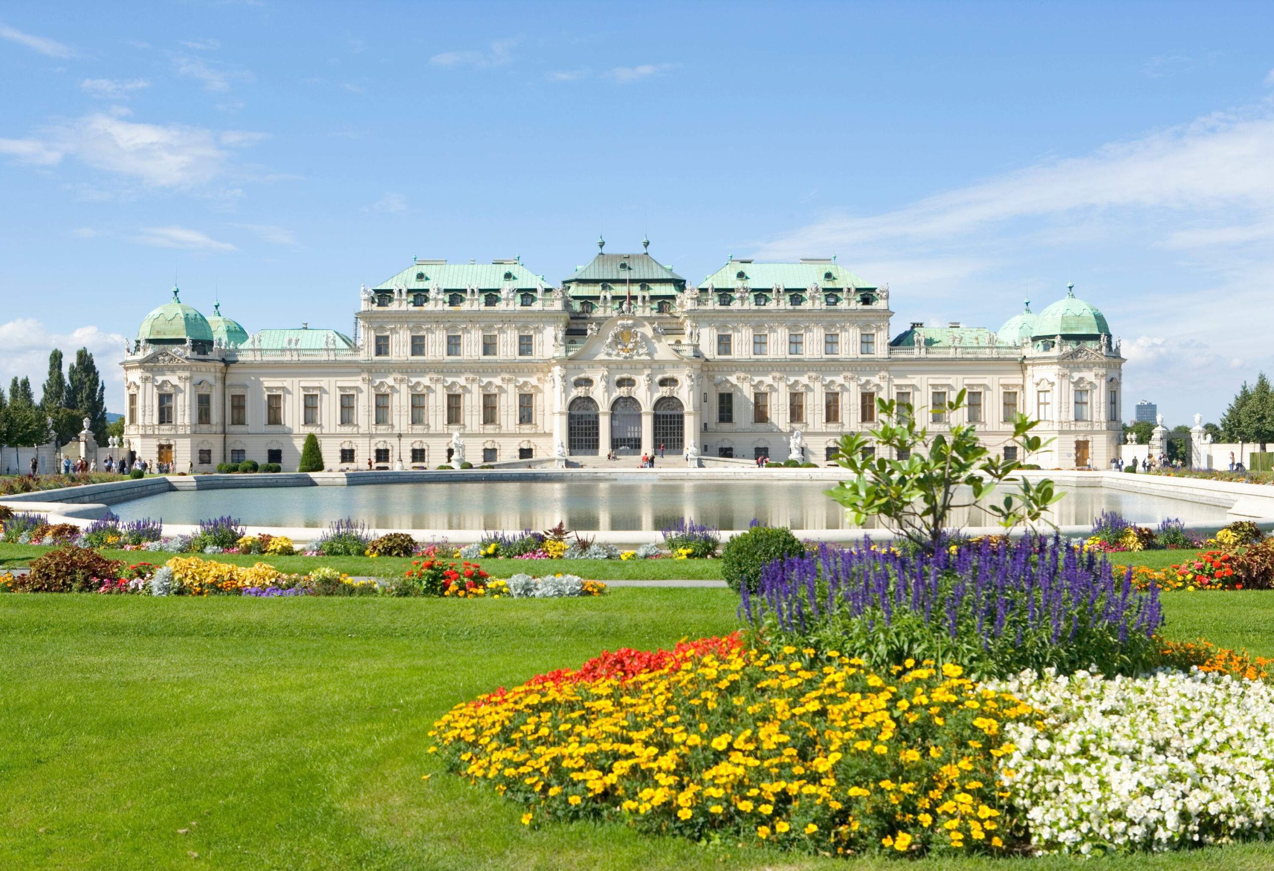 A lush and colourful garden with a lake in front of a historic Baroque palace.