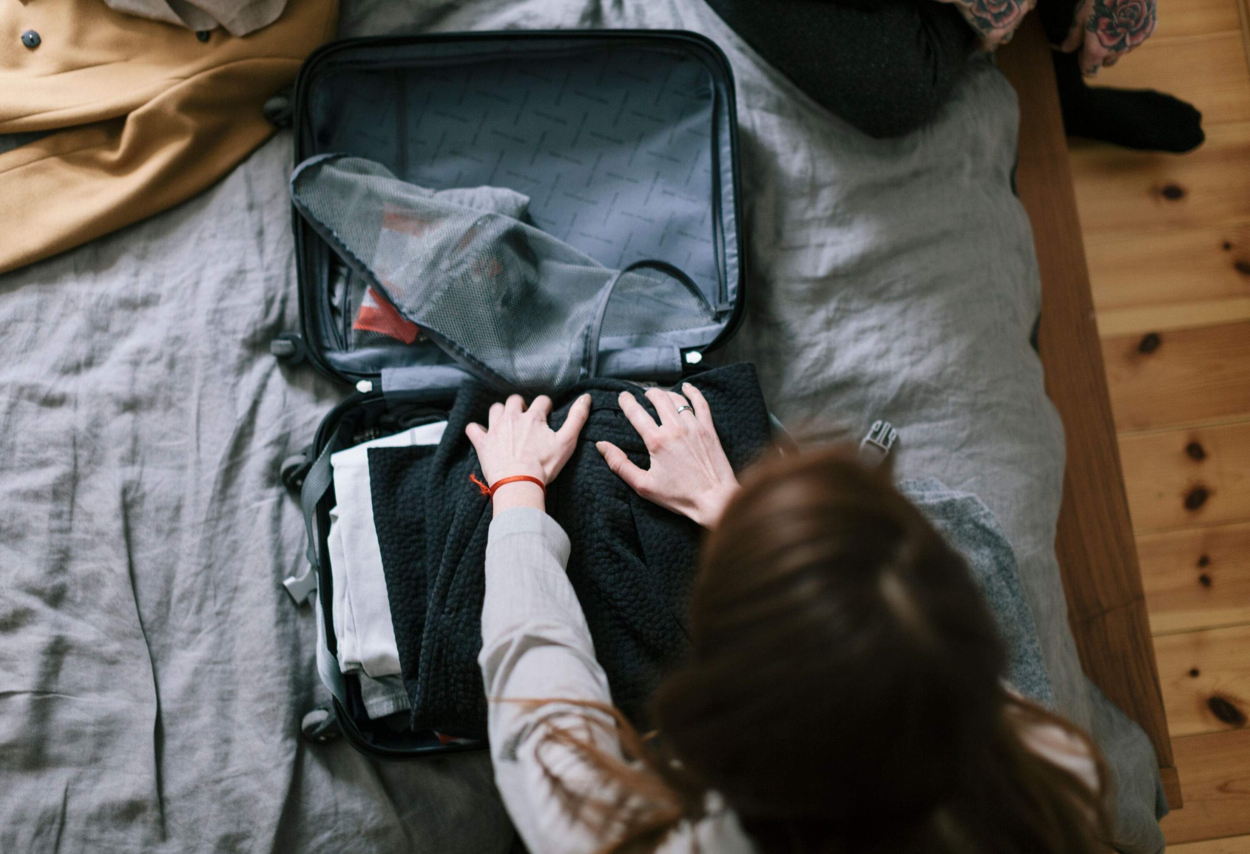 An individual put clothes in a small suitcase. 