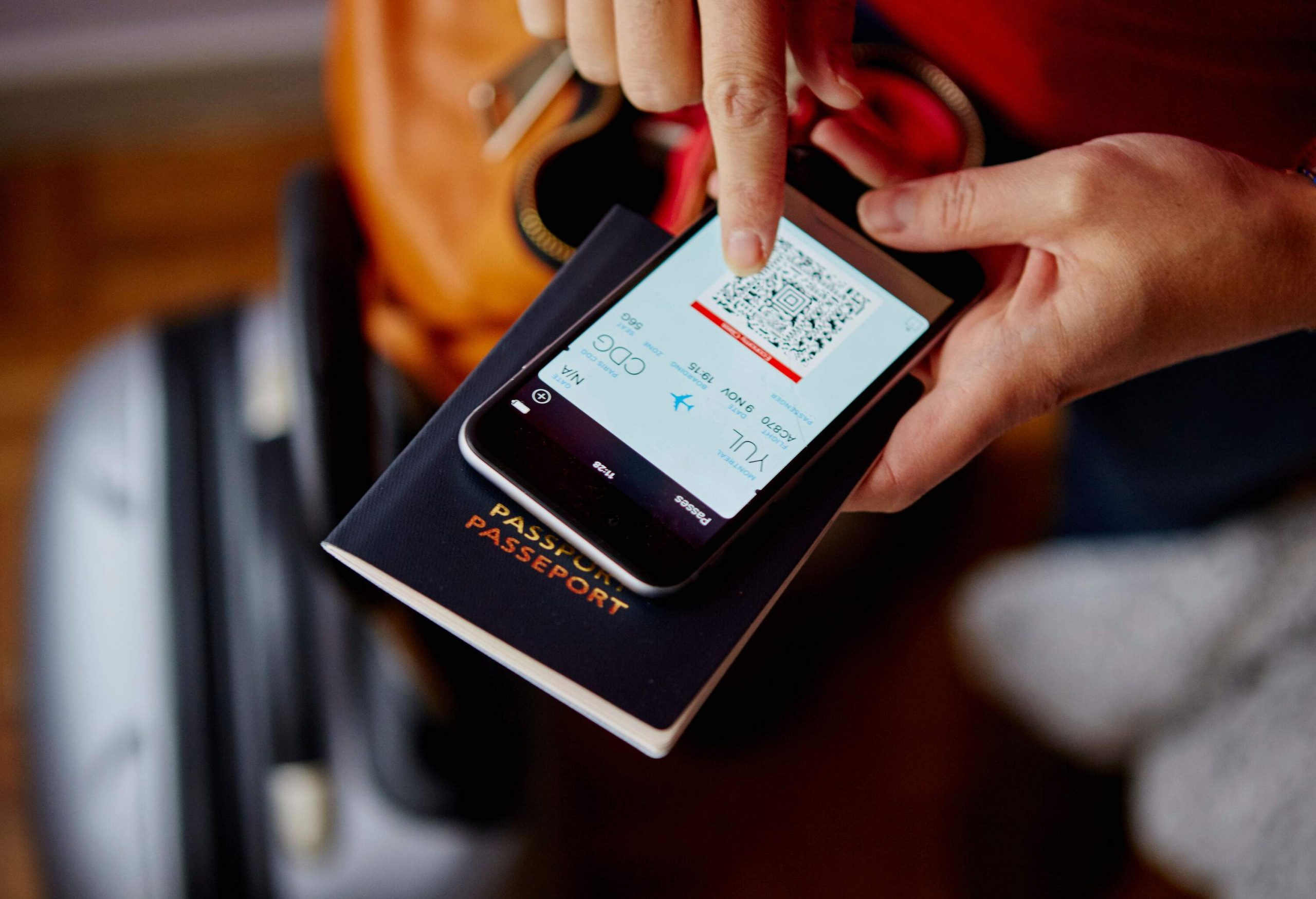 A person checks his flight QR code on his mobile device on top of his passport.