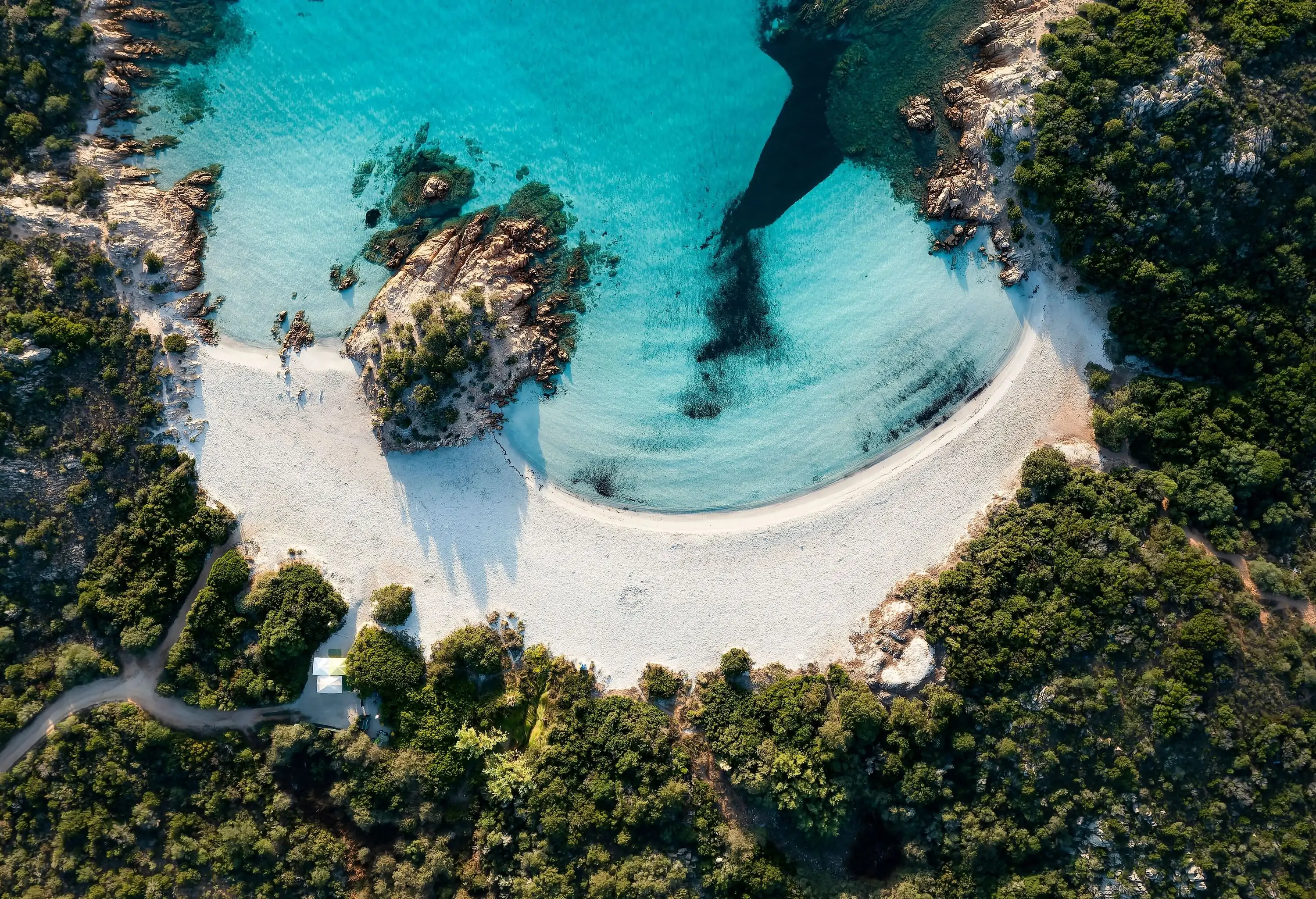 A secluded beach with a small white sand shore by the tranquil turquoise sea.