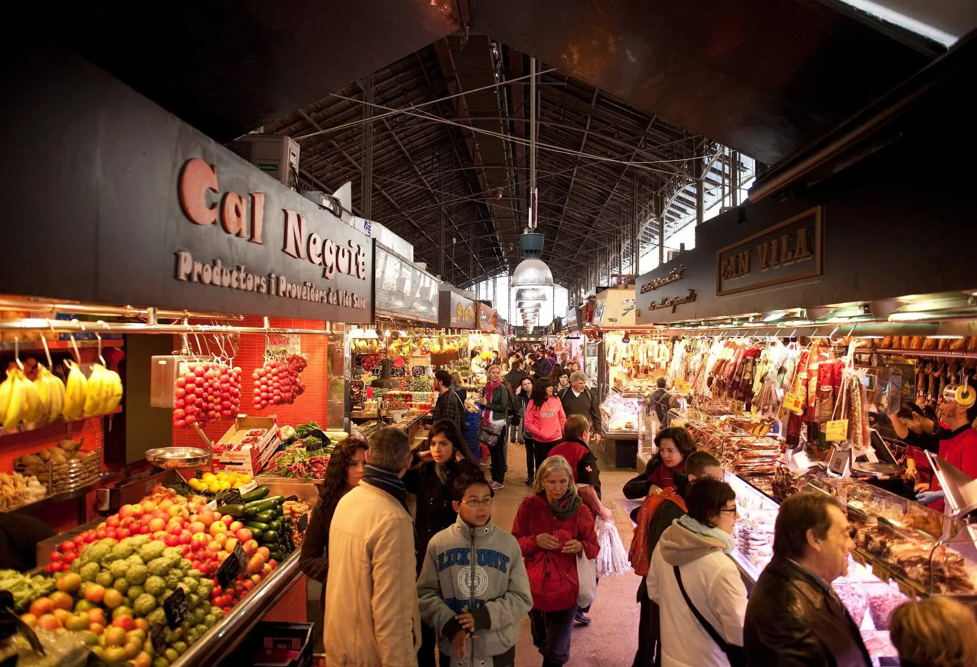 People strolling through stalls at a public market with a diverse selection of goods.
