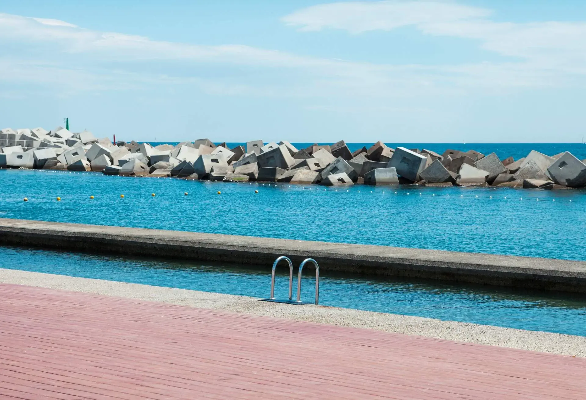 An ocean pool fenced by concrete stone breakwater blocks.