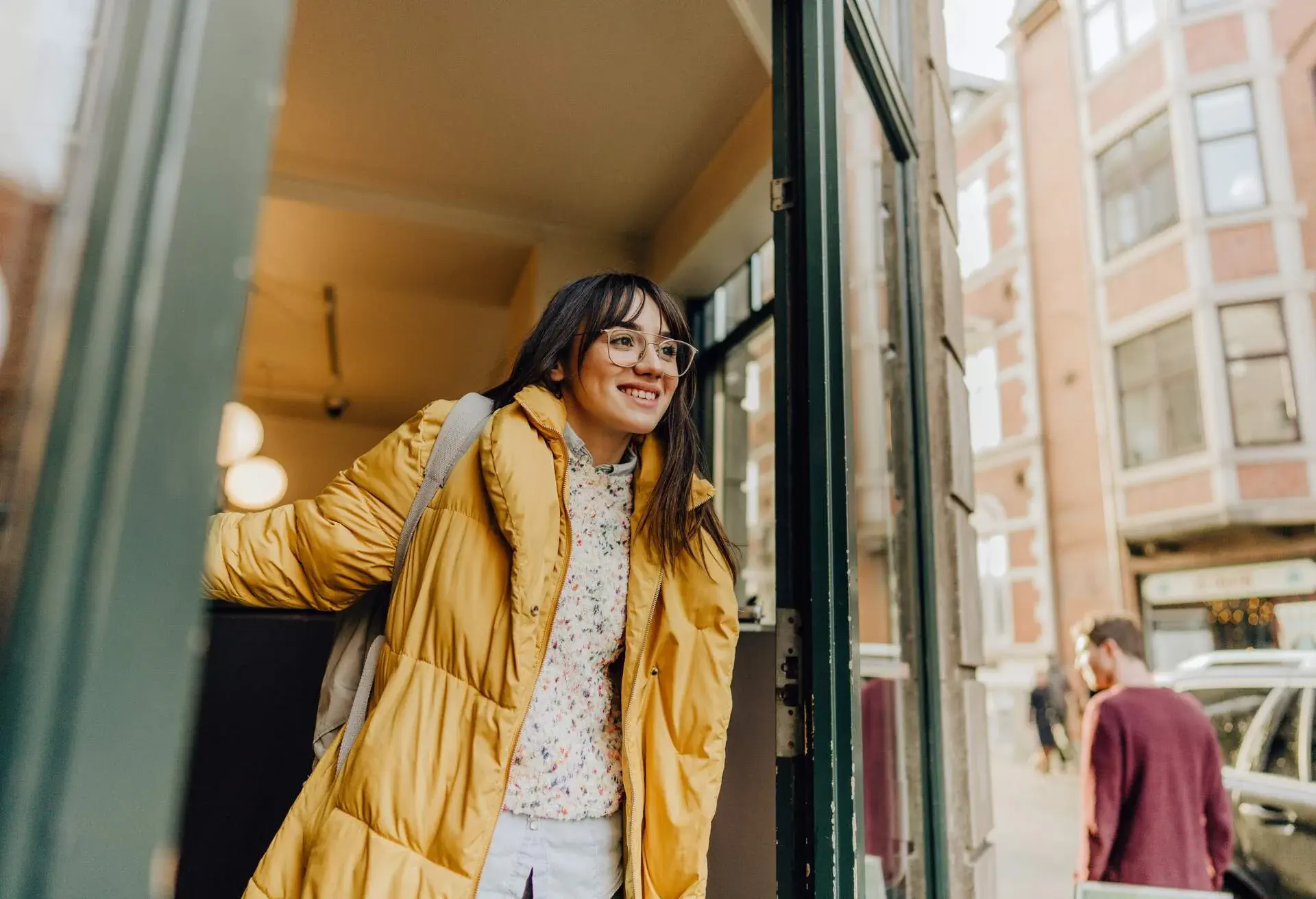 Photo of a smiling young woman leaving a shop