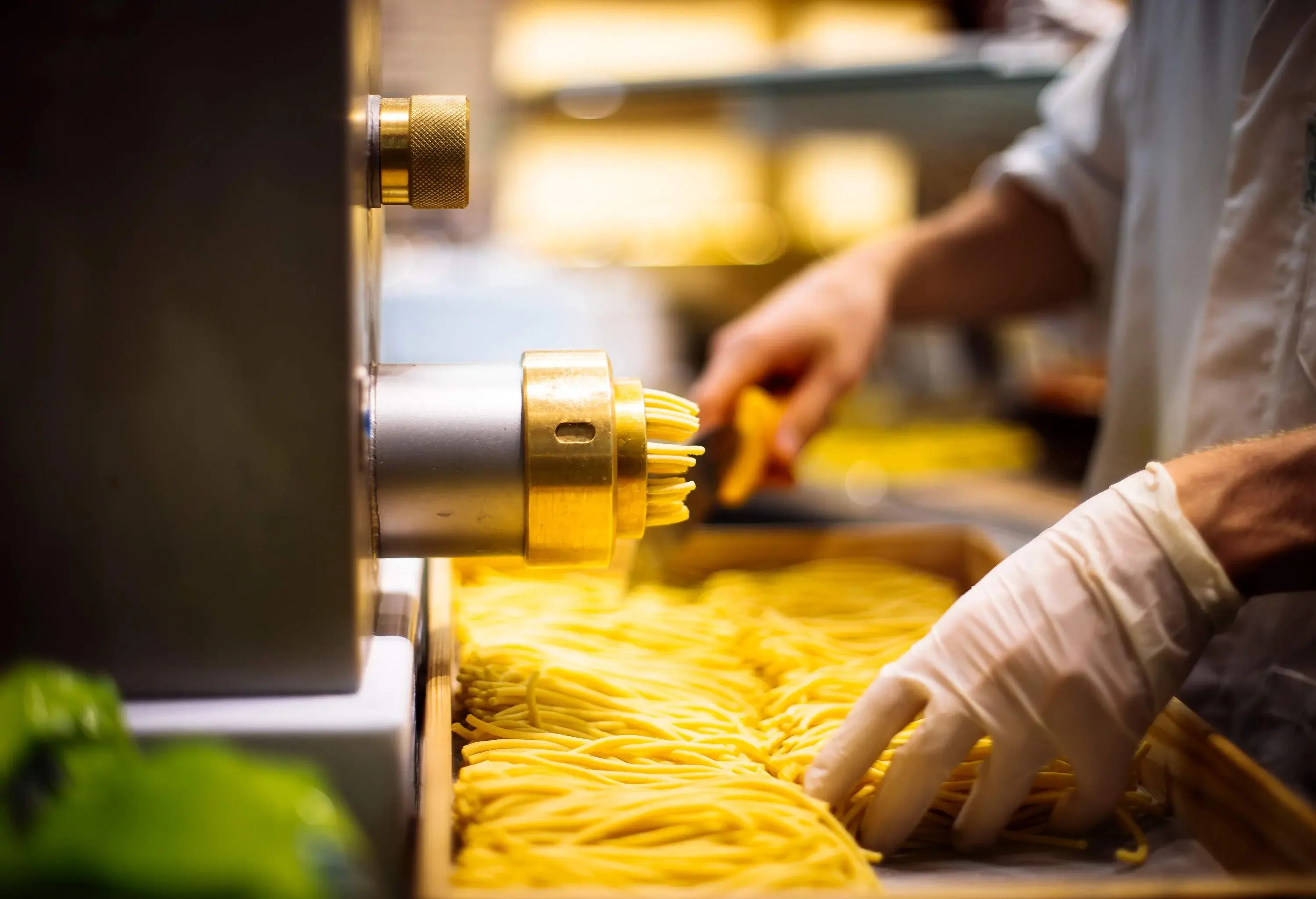 An individual uses a pasta machine to make fresh spaghetti.
