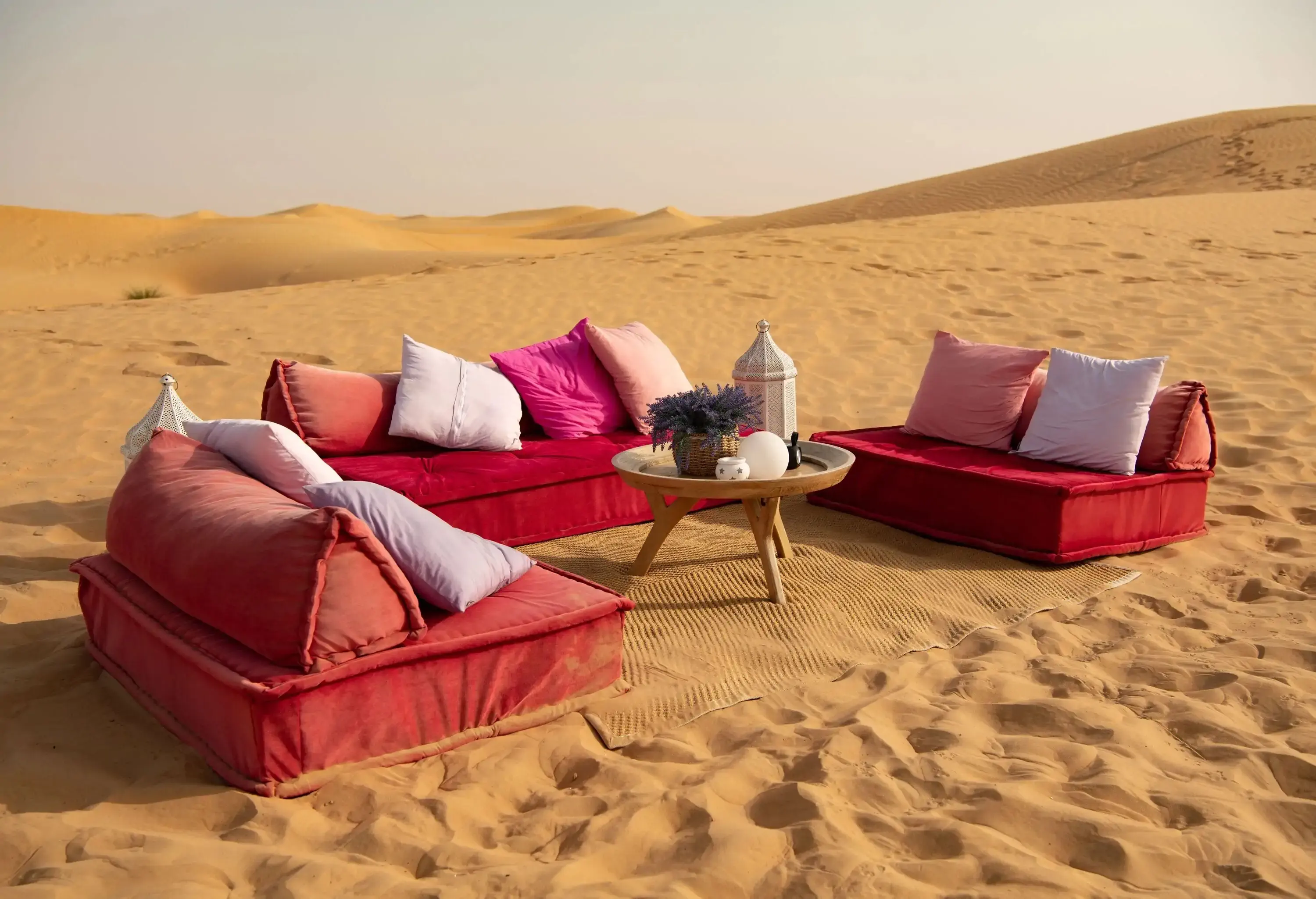 A mat in the desert with three couches around a coffee table.