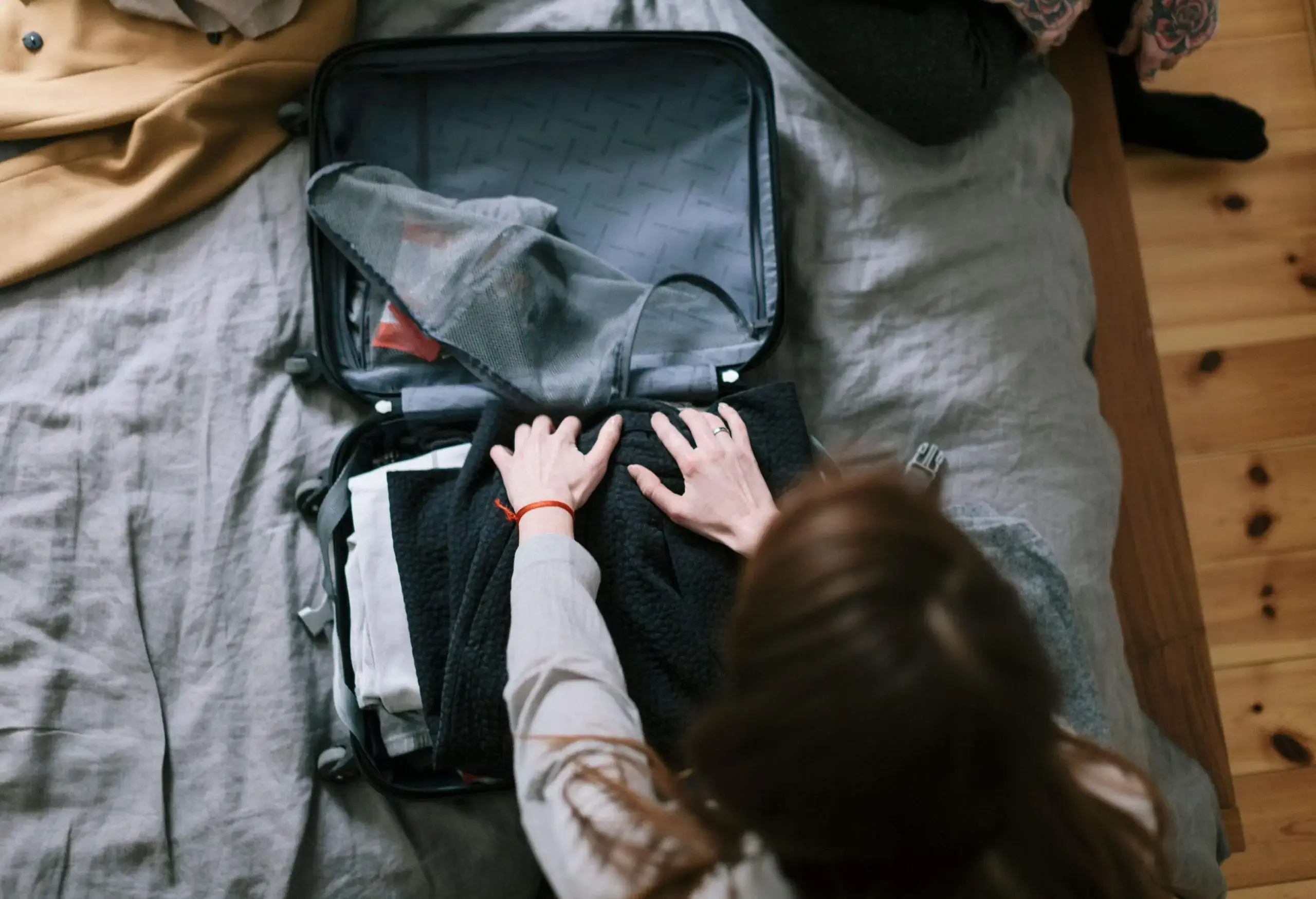 An individual put clothes in a small suitcase.
