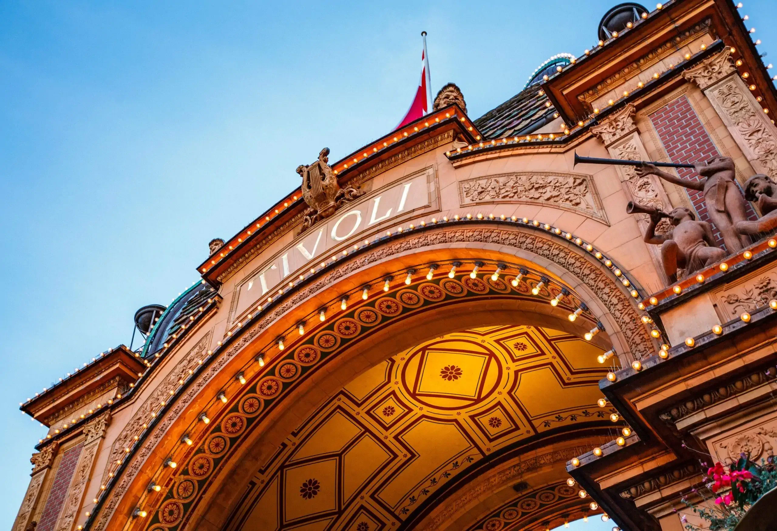 A gateway monument adorned with intricate sculptures and lighting with the words 