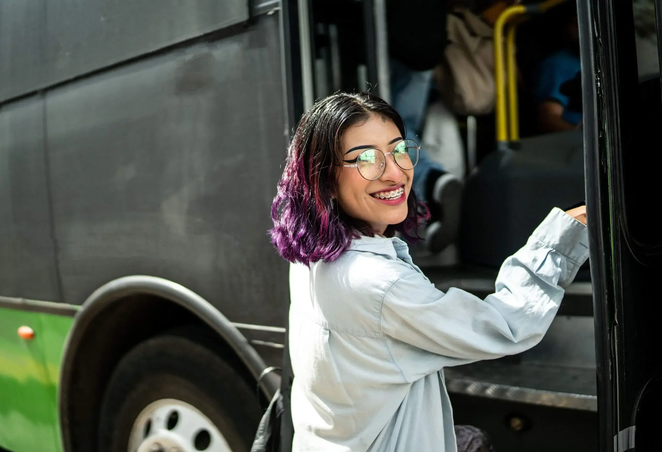 A woman wearing glasses preparing to board a bus.