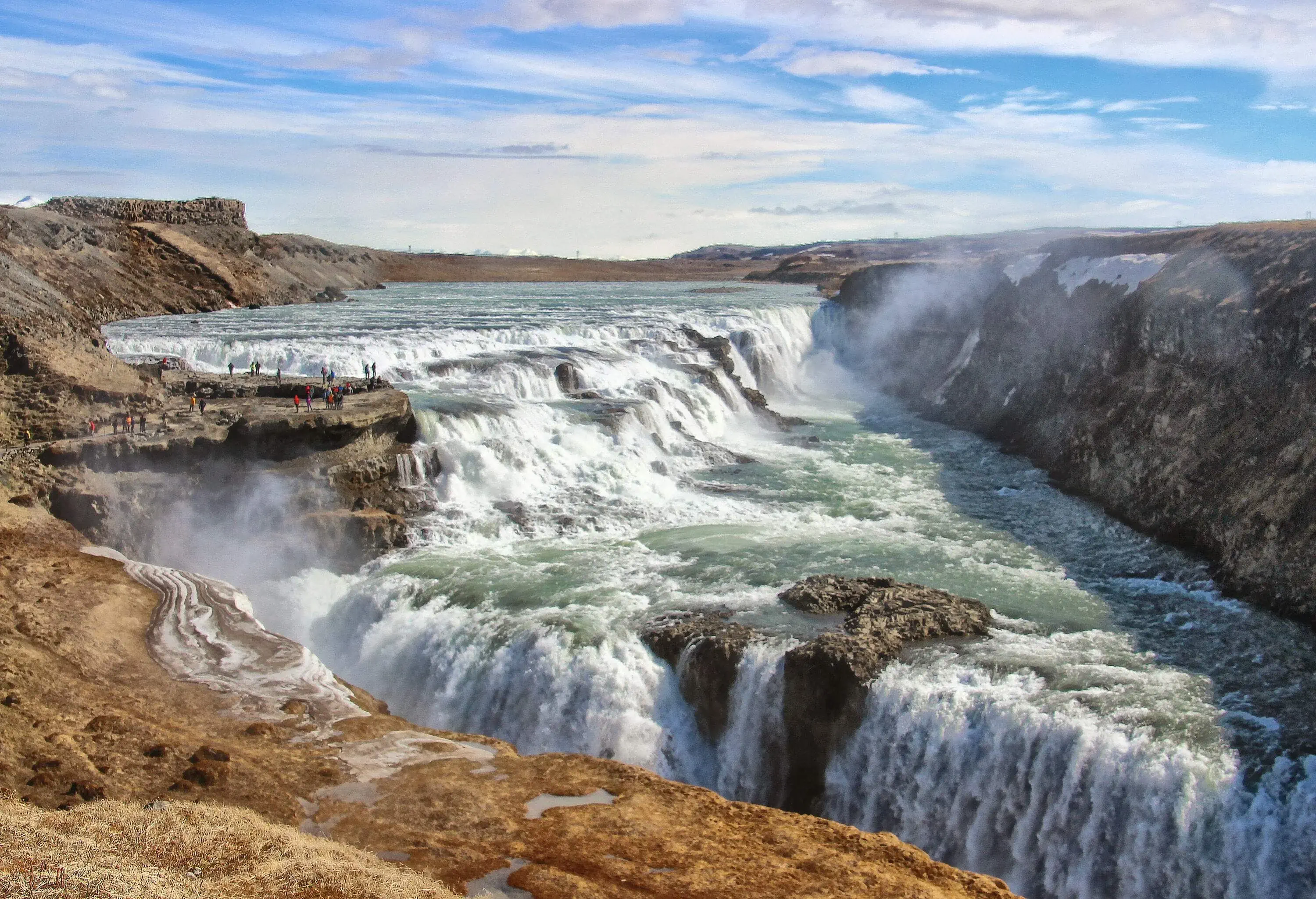 Gullfoss waterfall, a magnificent natural wonder in Iceland, cascades over two tiers of rugged rock formations, creating a stunning display of powerful water currents and mist that takes one's breath away.