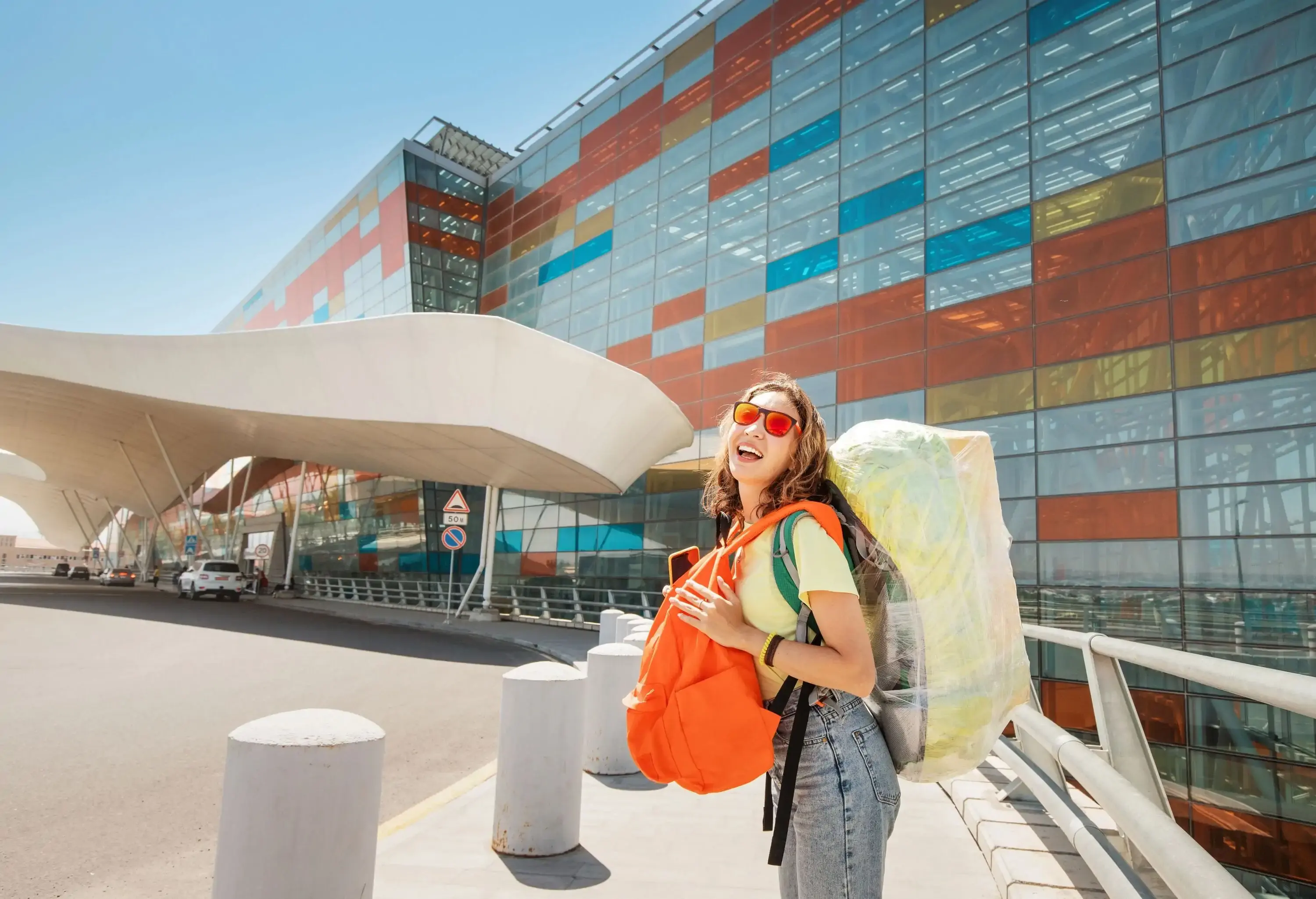 woman with two large backpacks packed in plastic tape hurries to her plane to the airport
