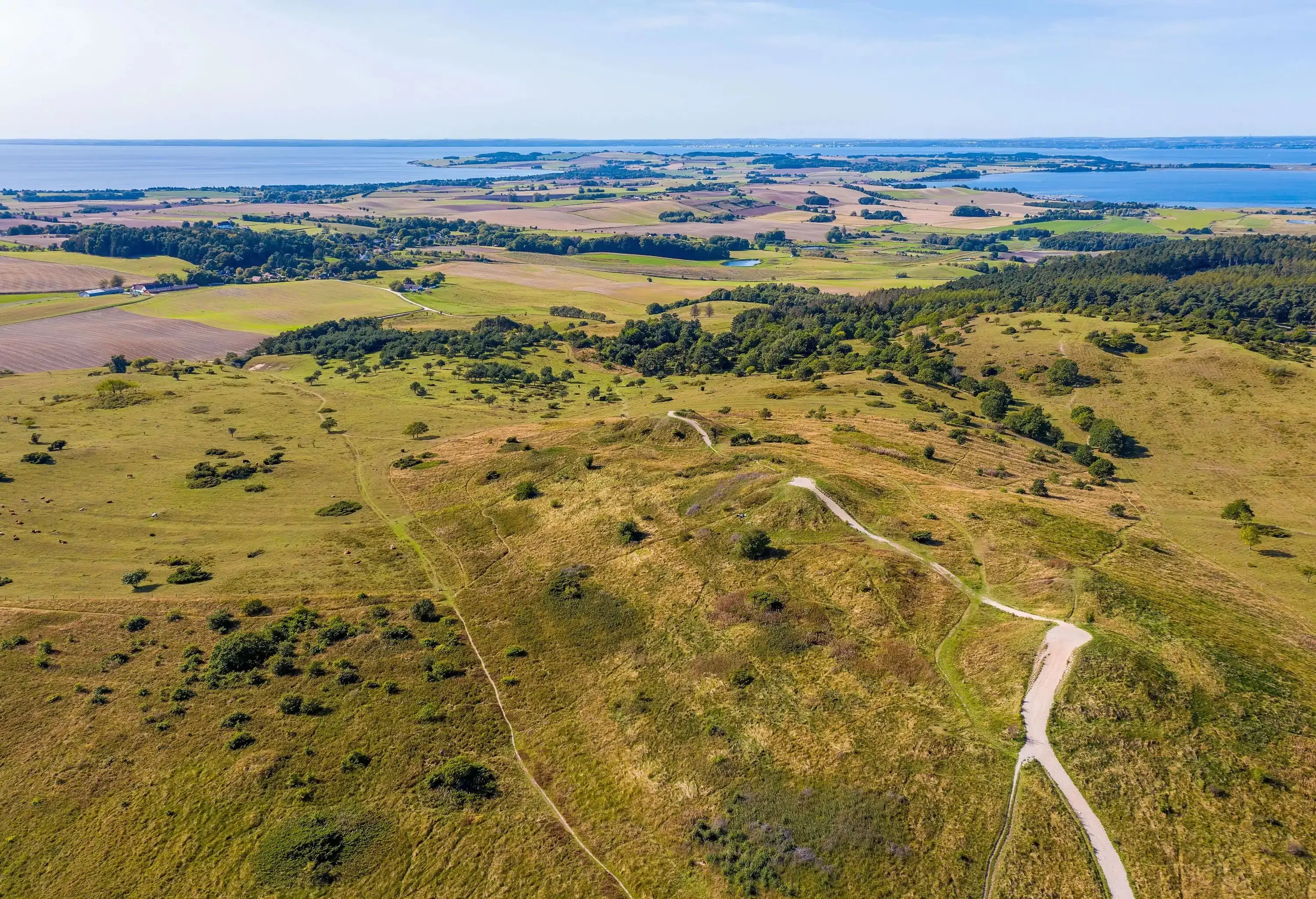 Mols Hills, Denmark - September 17, 2020 - Trehøje seen from above. The three Bronze Age mounds of Trehøje, 127 metres above sea level, offer a panorama view from Aarhus to Ebeltoft, including four inlets: Kalø, Begtrup, Knebel and Ebeltoft. From up here you can see the National Park’s border to the south west, where fertile clay once deposited by the ice means the land is intensely farmed, as opposed to the nutrient-poor sand left by the ice on the hills and on the coastline along Ebeltoft Vig.