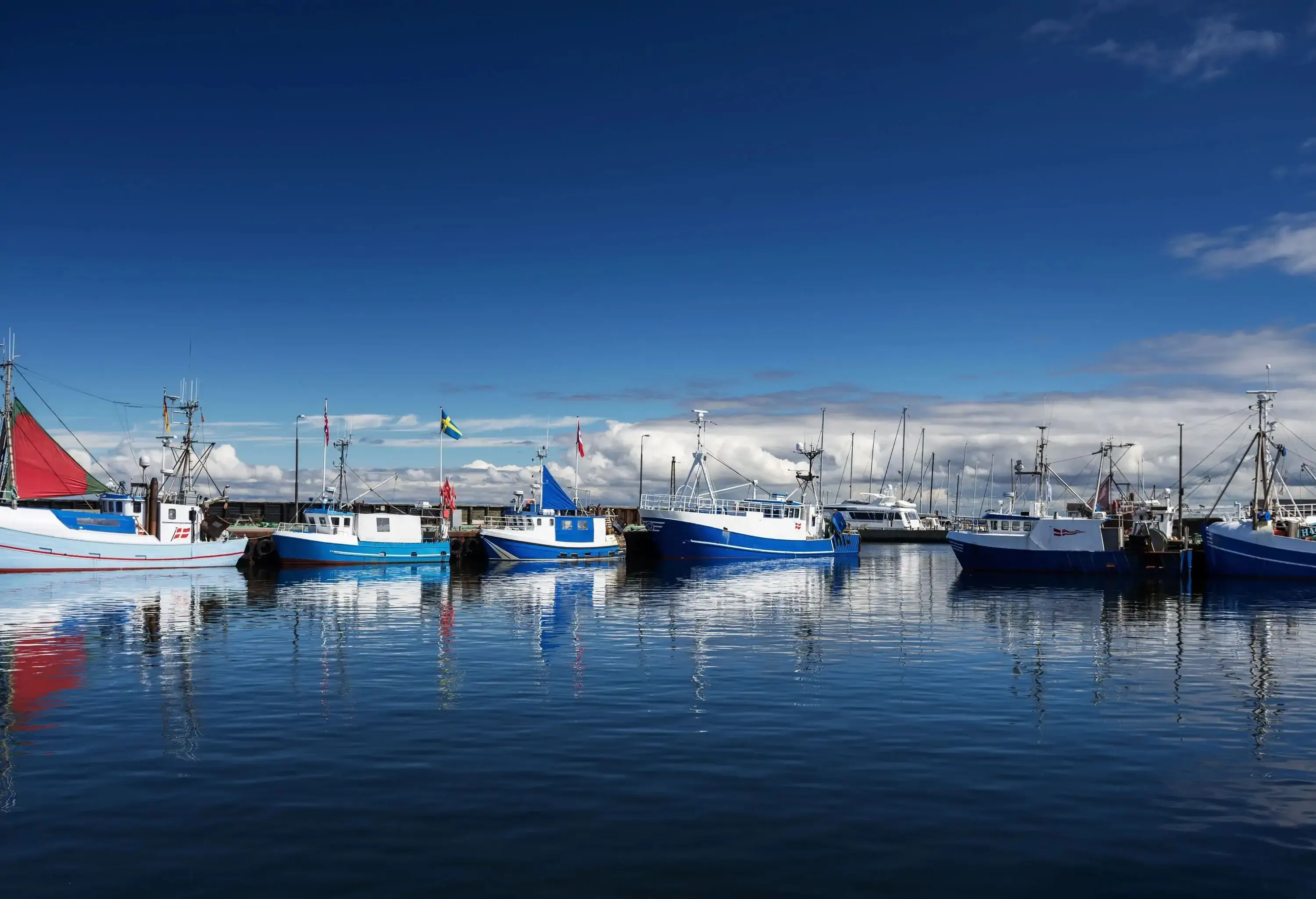 Boats moored in a harbour loomed over by a dark blue sky.