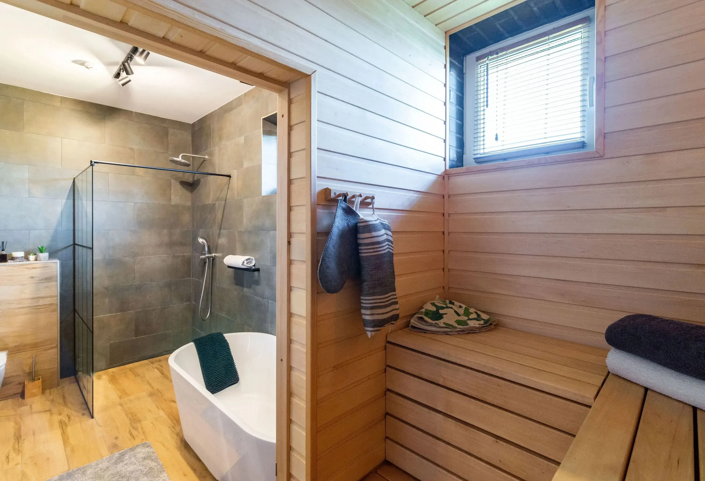 View from sauna through open door to bathroom with bathtub and shower.