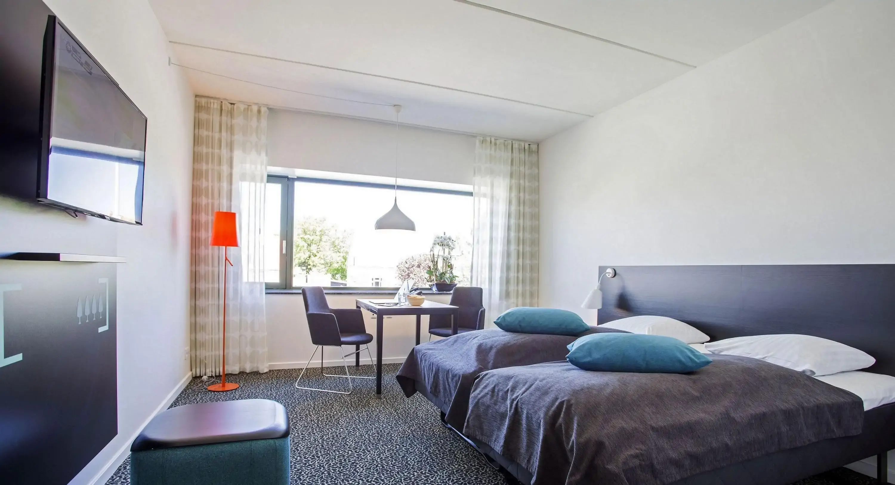 Modern hotel room interior with separate beds and a desk with two chairs by a window