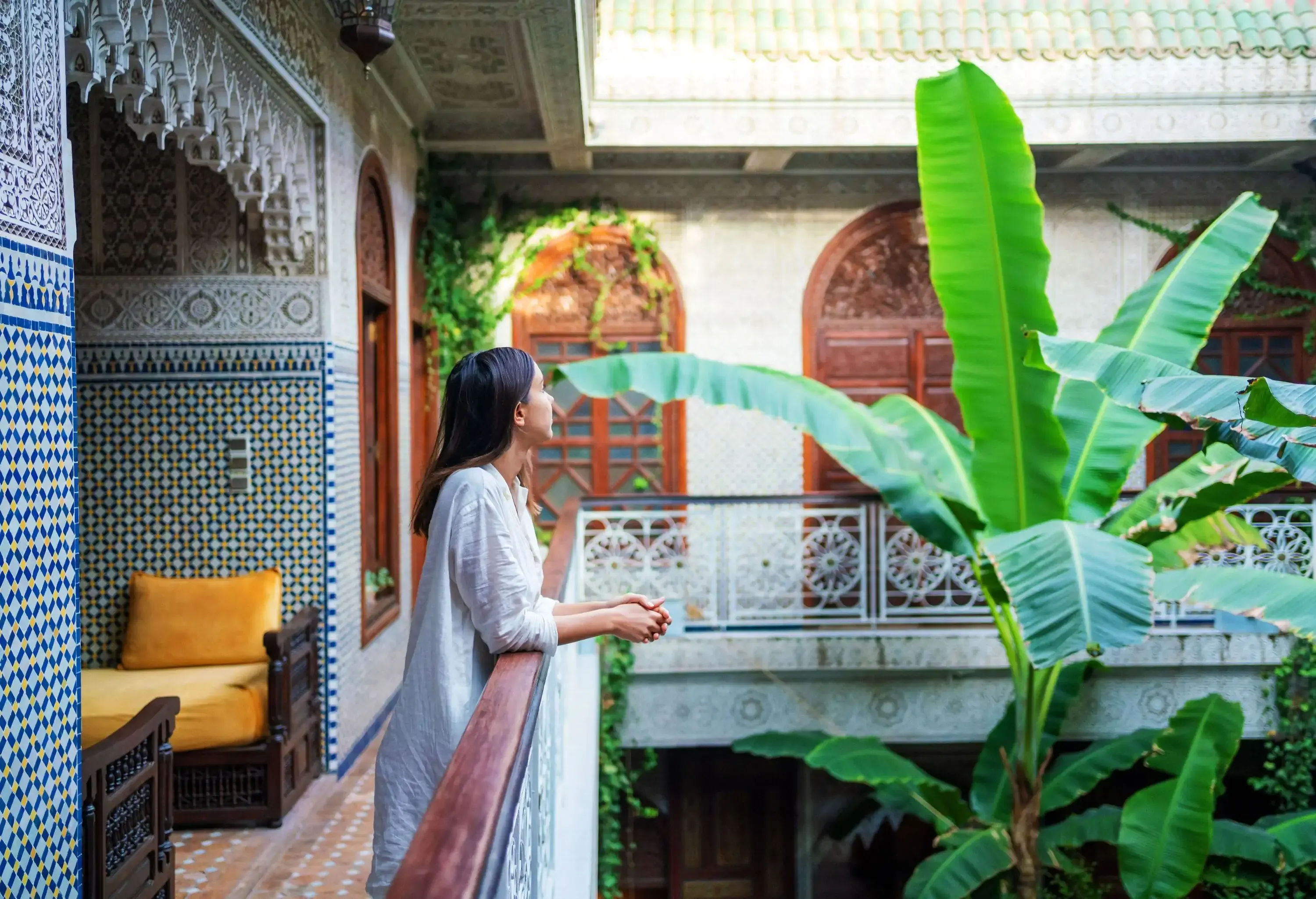 A female tourist deep in thought leans her arms on the balcony.