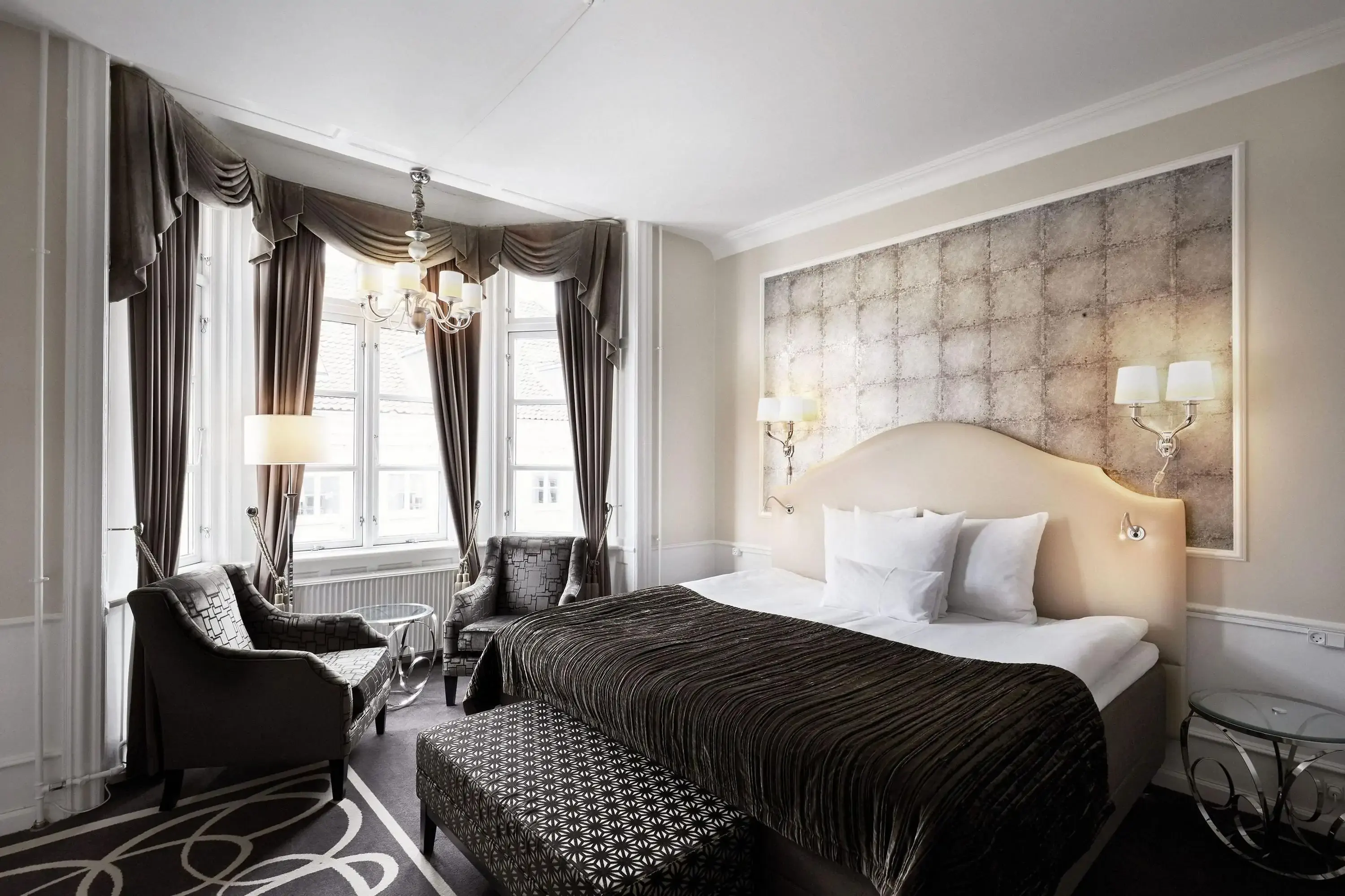 Elegant modern hotel room with chandelier and lavish curtains with dark soft furnishings