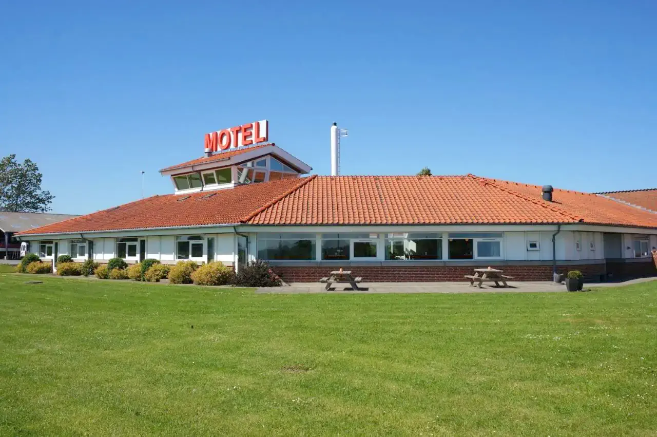 Exterior of a motel with a a large meadow on a sunny day