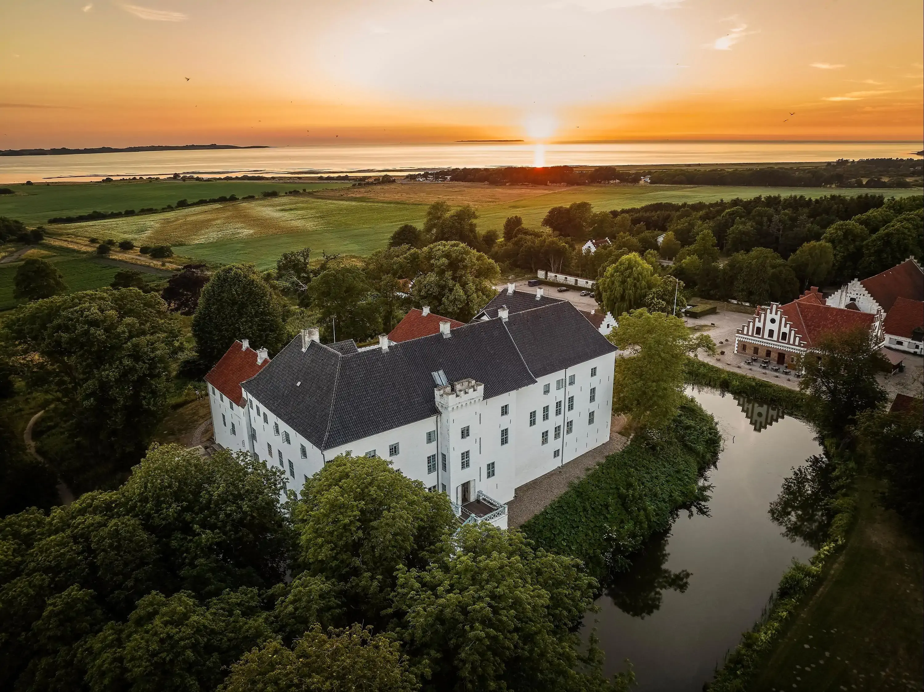 Aerial view of a castle with the sea in the background at sunset