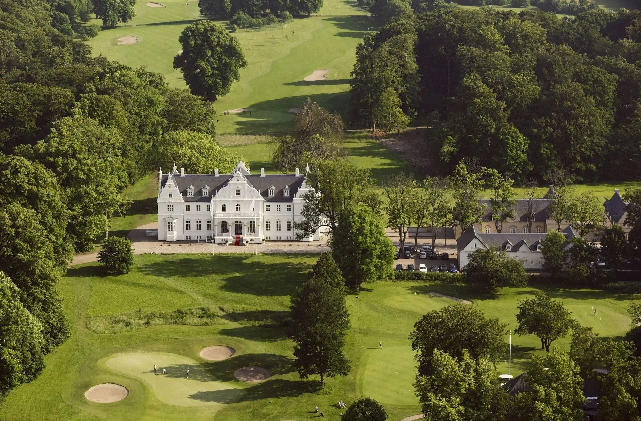 Aerial view of a white castle surrounded by green lawns and a golf course