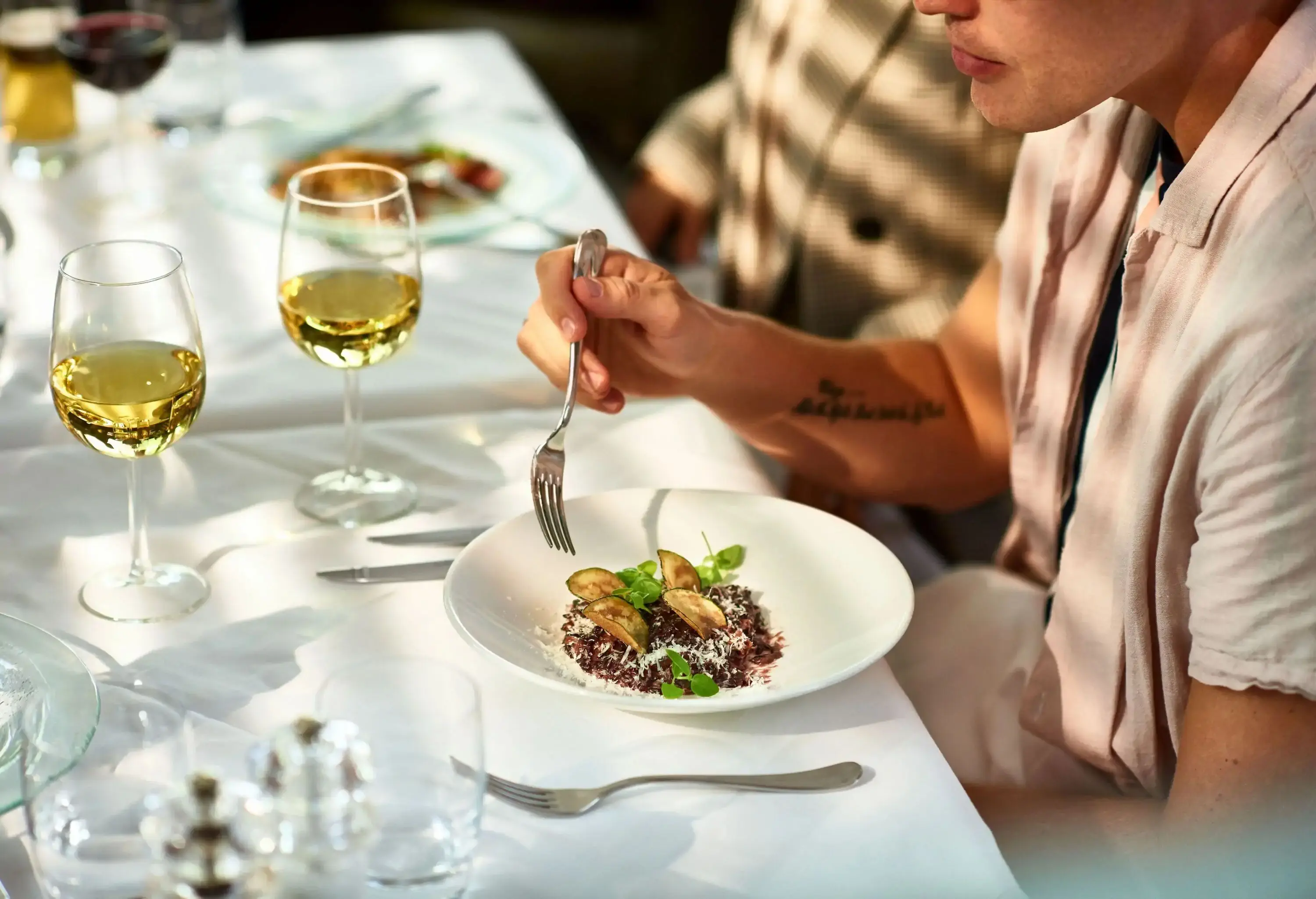 A man eating a gourmet meal with white wine in a restaurant.