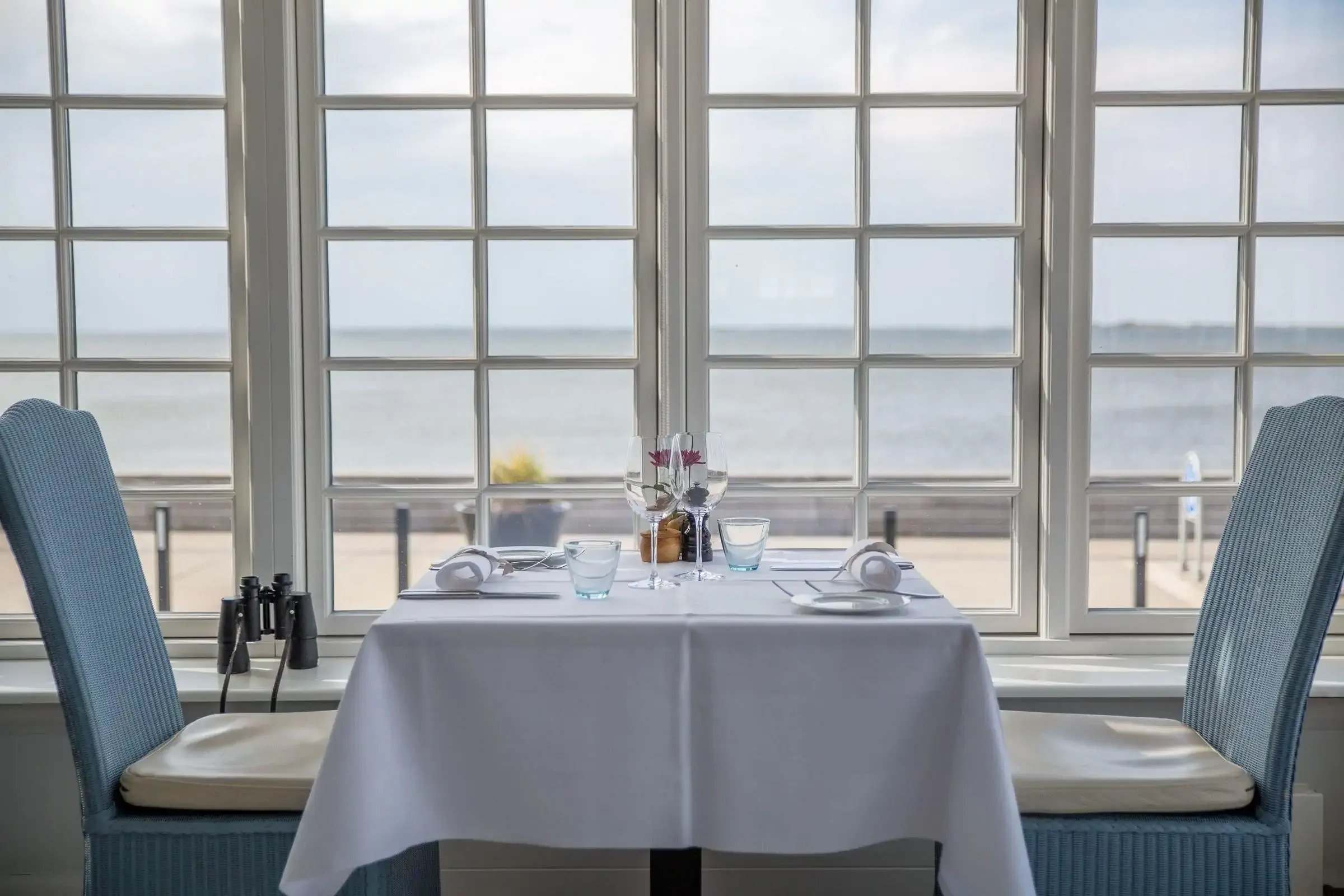 A set table in front of a window with sea view