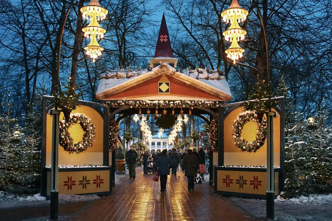 Entrance to a hotel complex and amusement park decorated for Christmas, people passing by