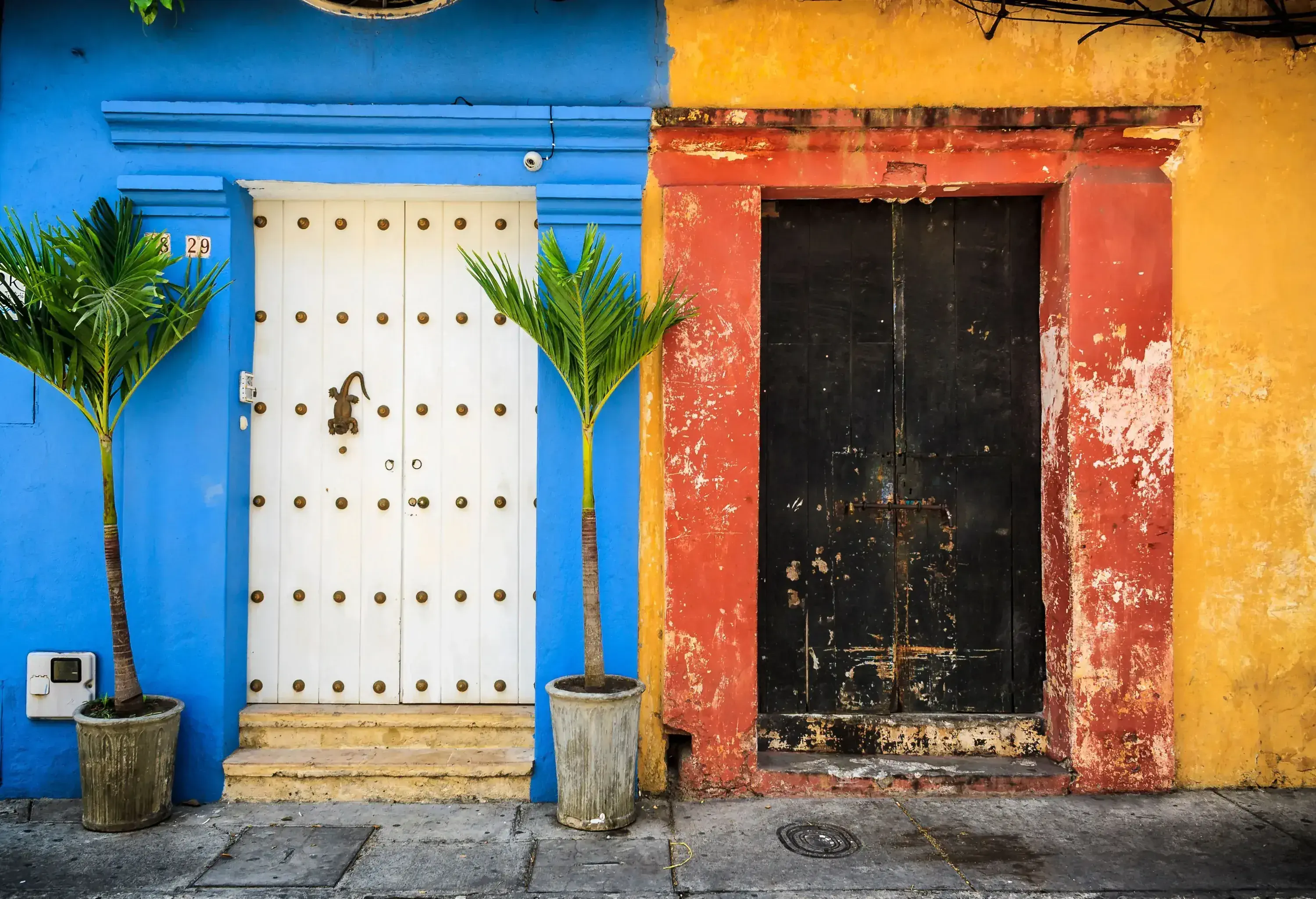 A blue residence with a white door beside a yellow residence with a black door.