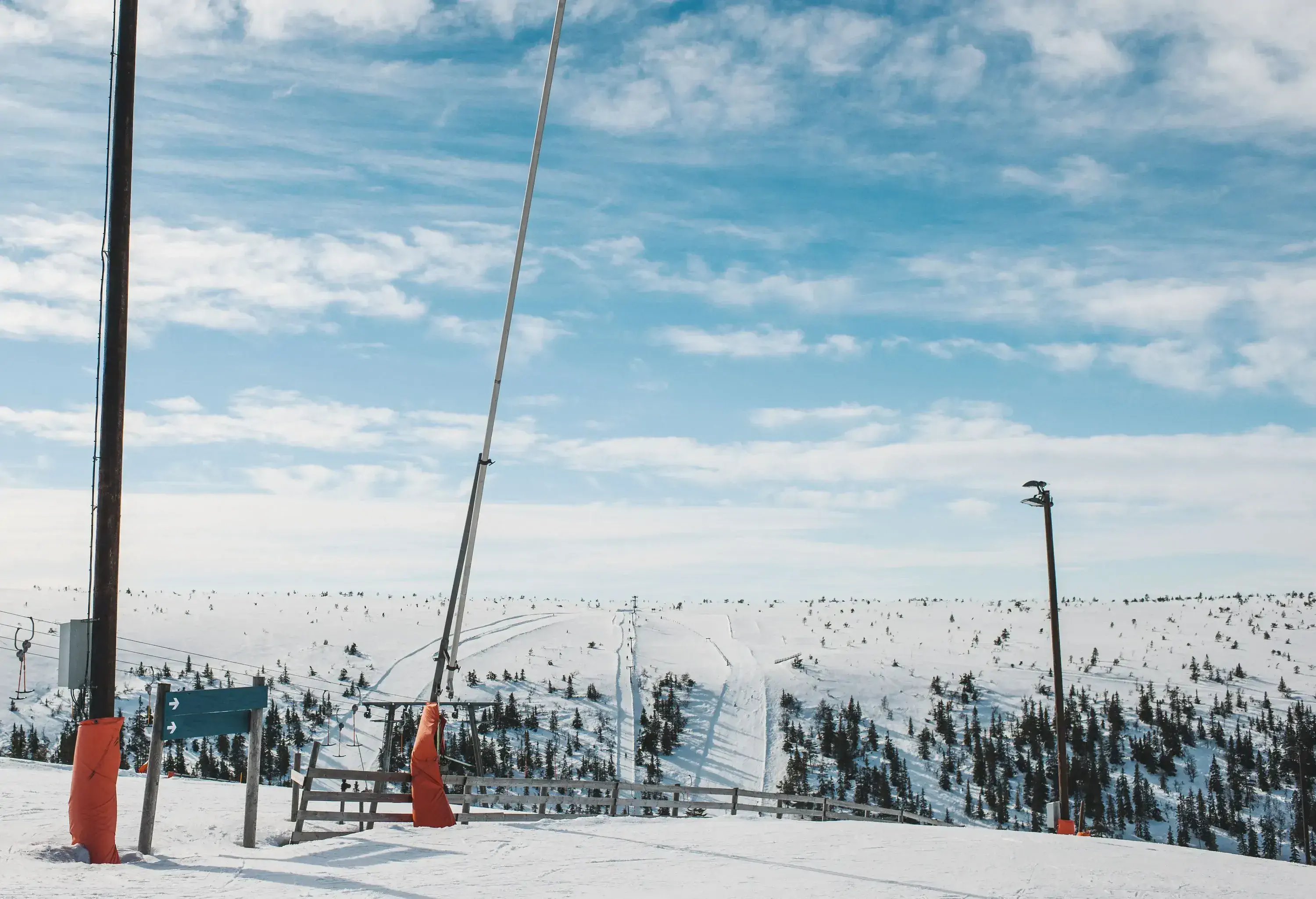 Ski slopes covered in white powder of snow against a wispy-clouded sky.