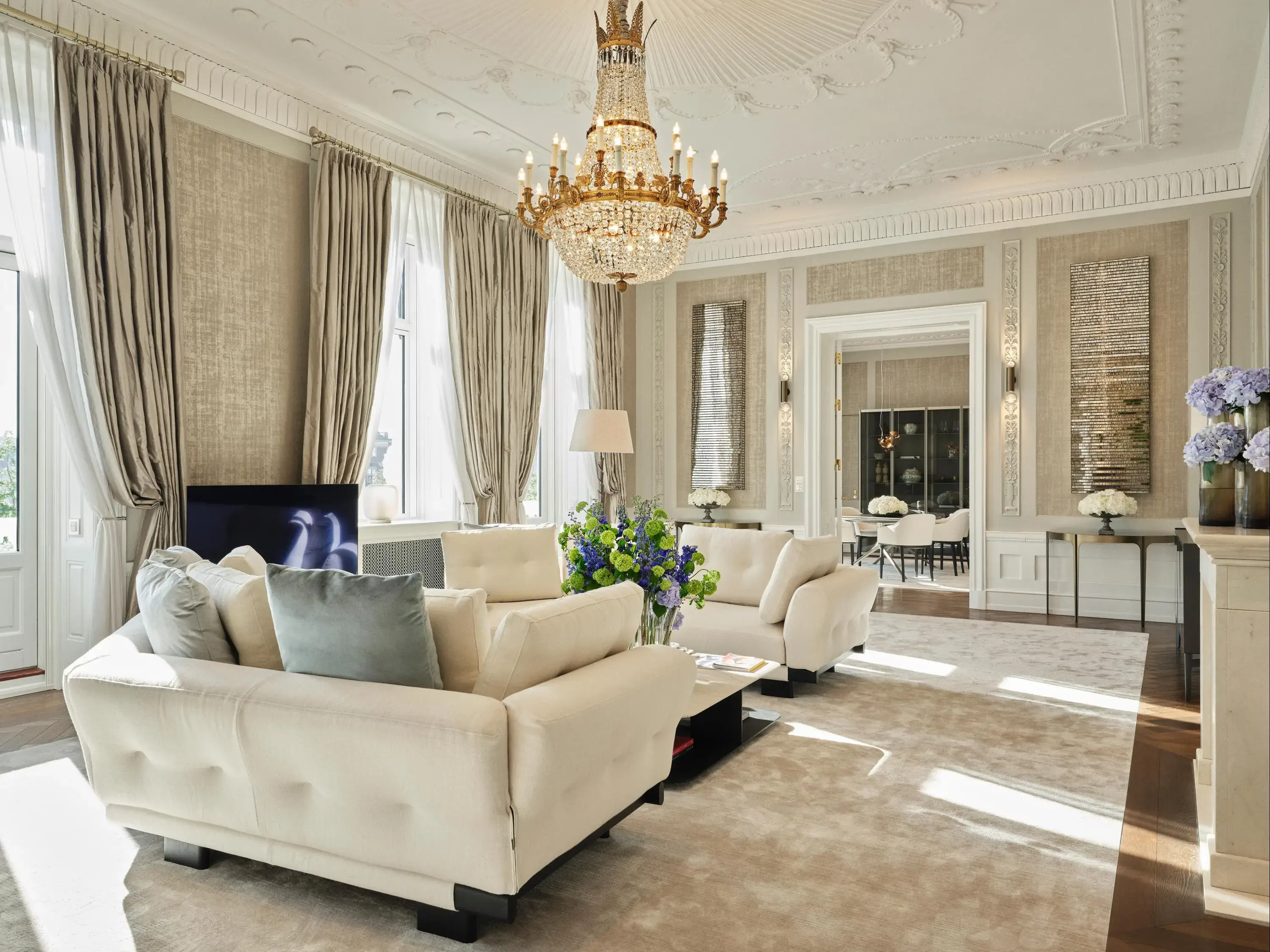 A luxury hotel lounge decorated in neutral tones and a large gold and crystal chandelier