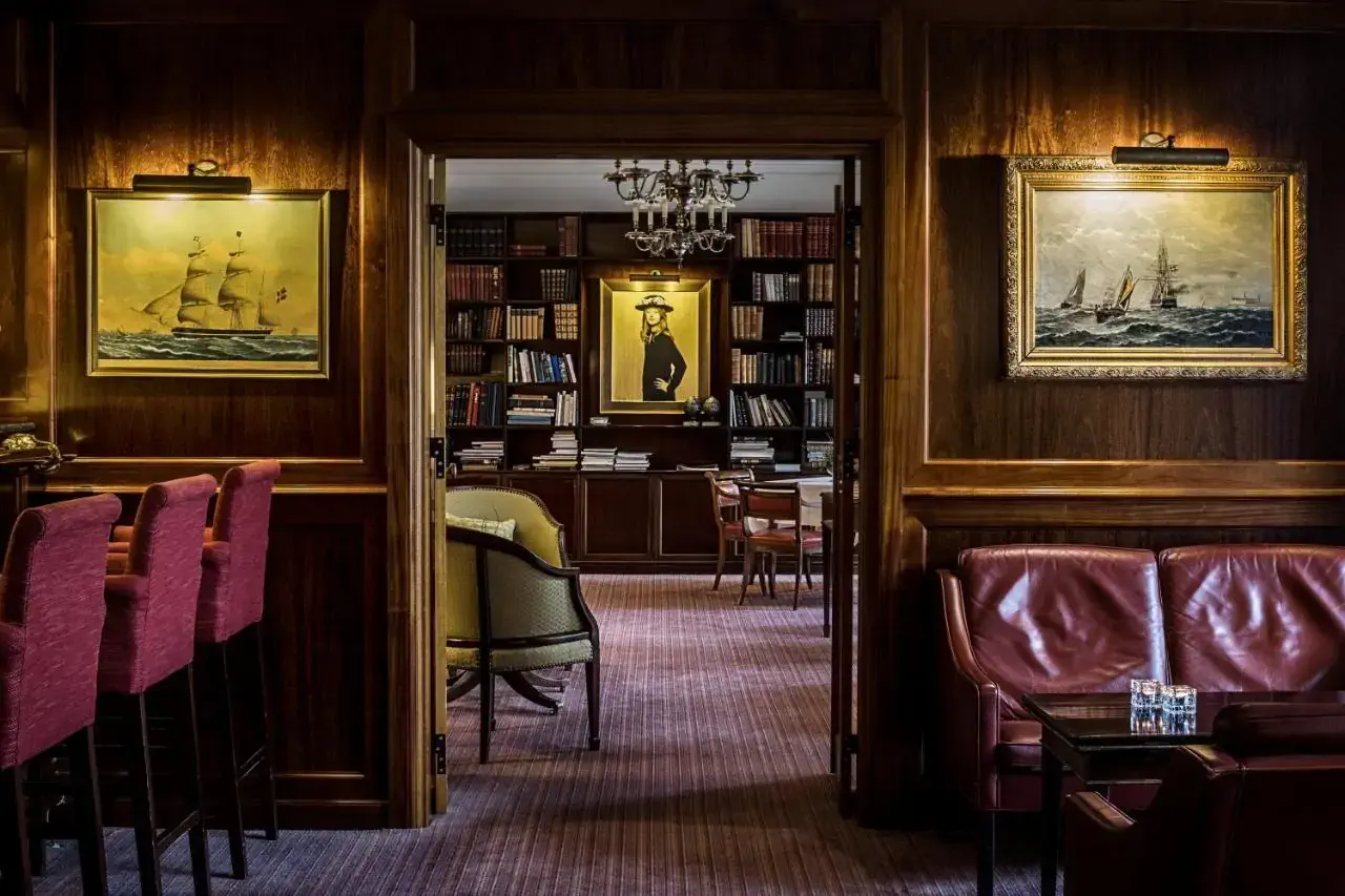 A dark wooden library room seen through an entryway with wooden panelling