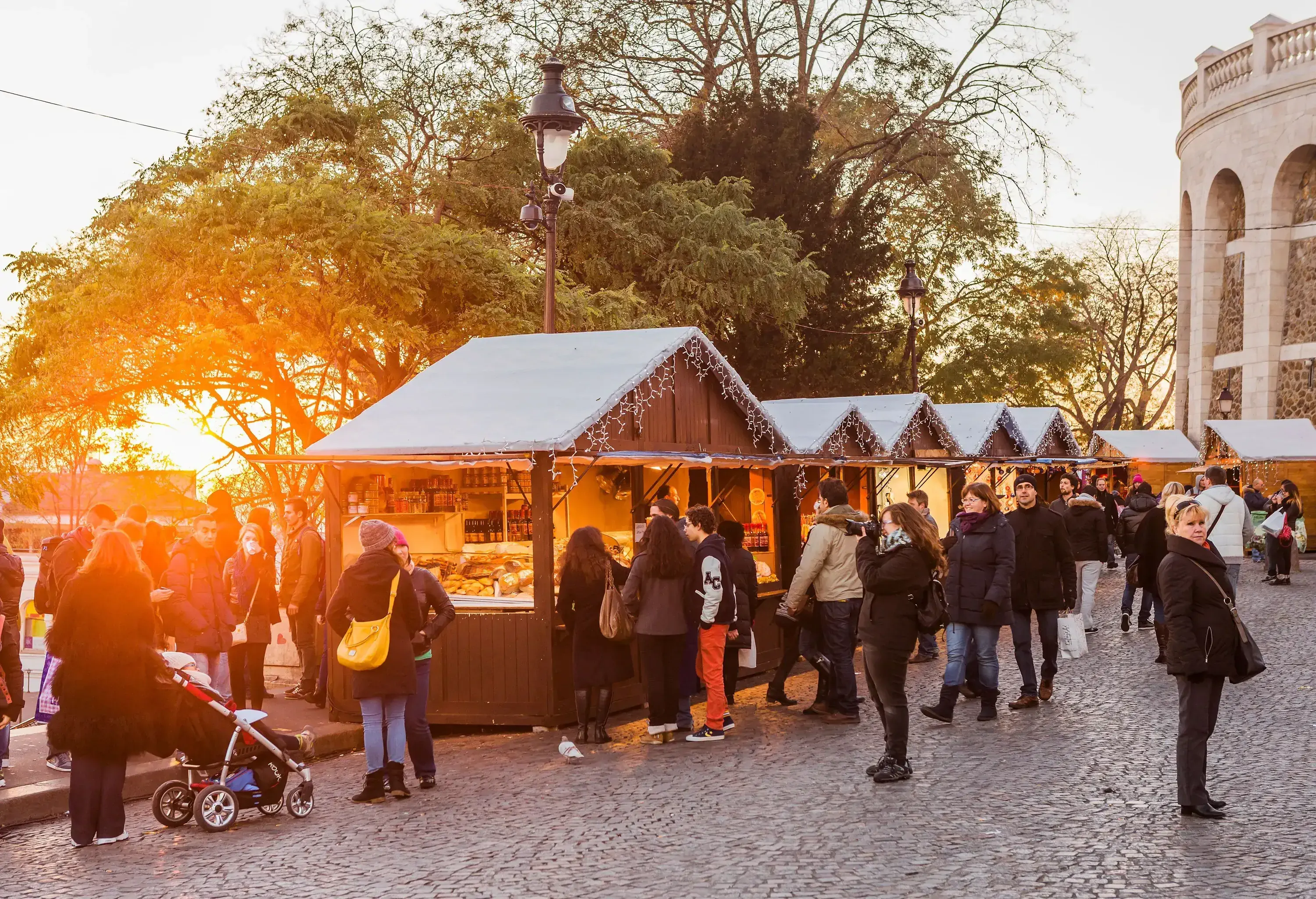 People strolling and looking over stores at a small Christmas market.