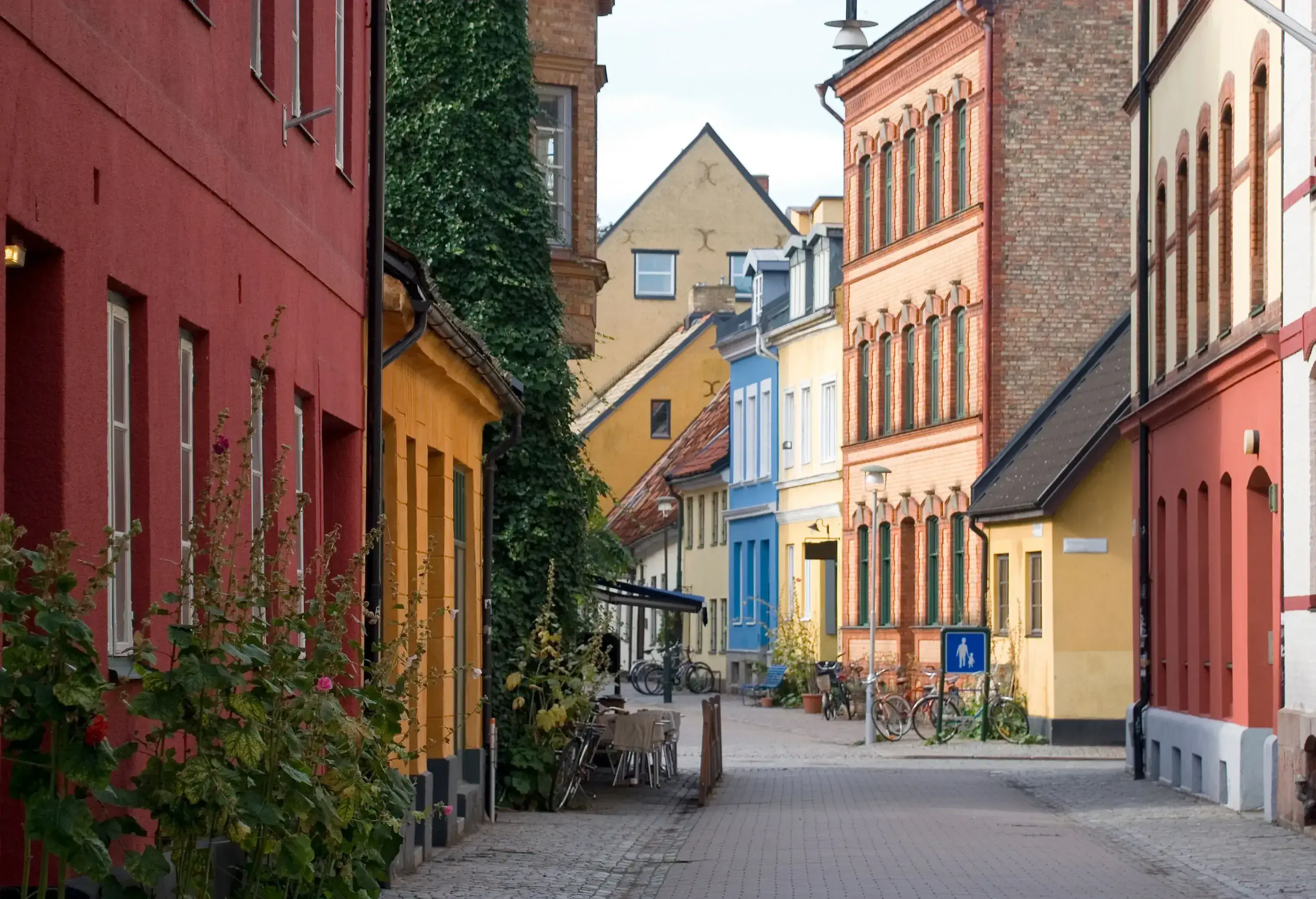 Bicycles parked along a narrow street in the middle of colourful buildings.