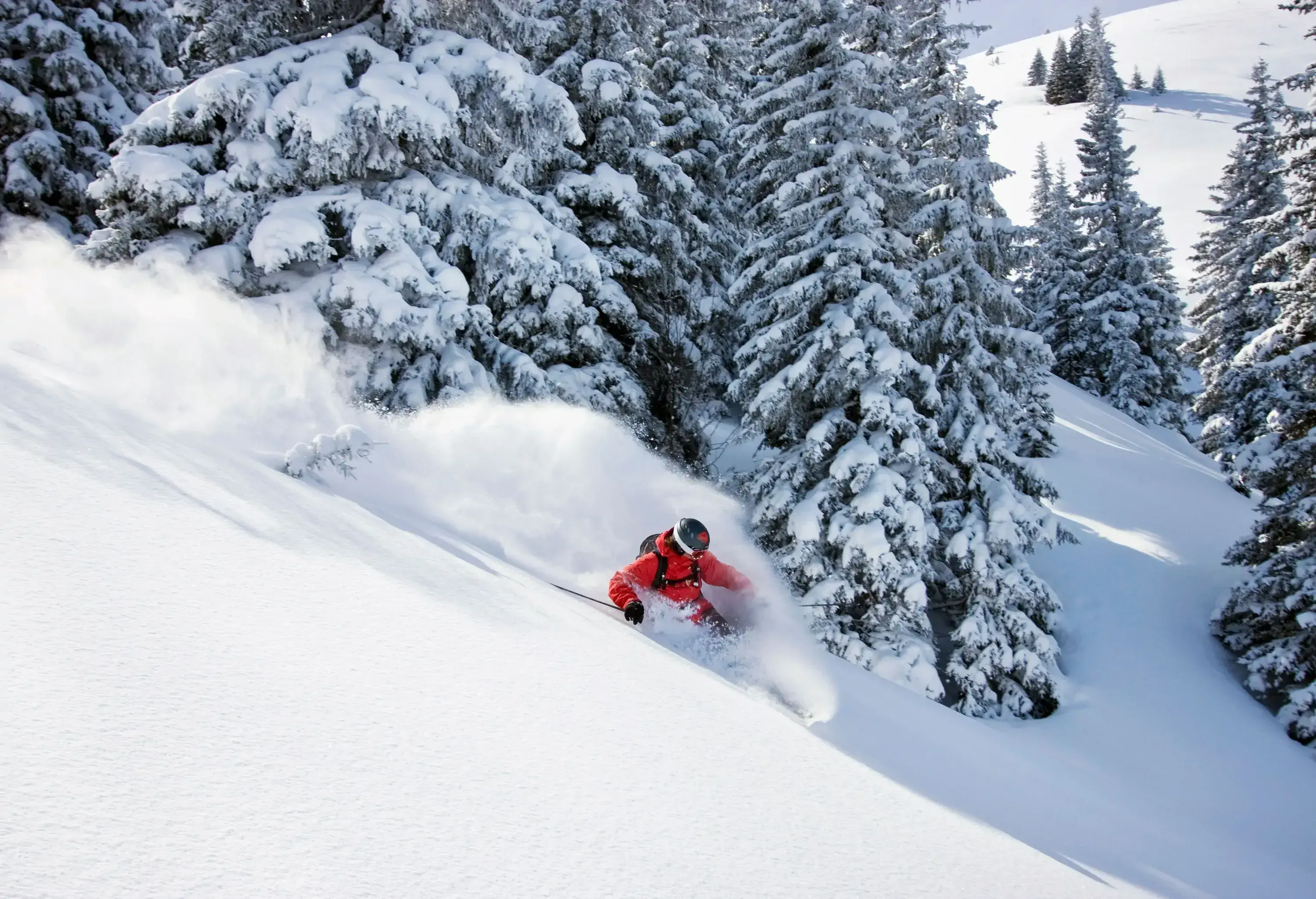 A skier going down a steep ski slope.