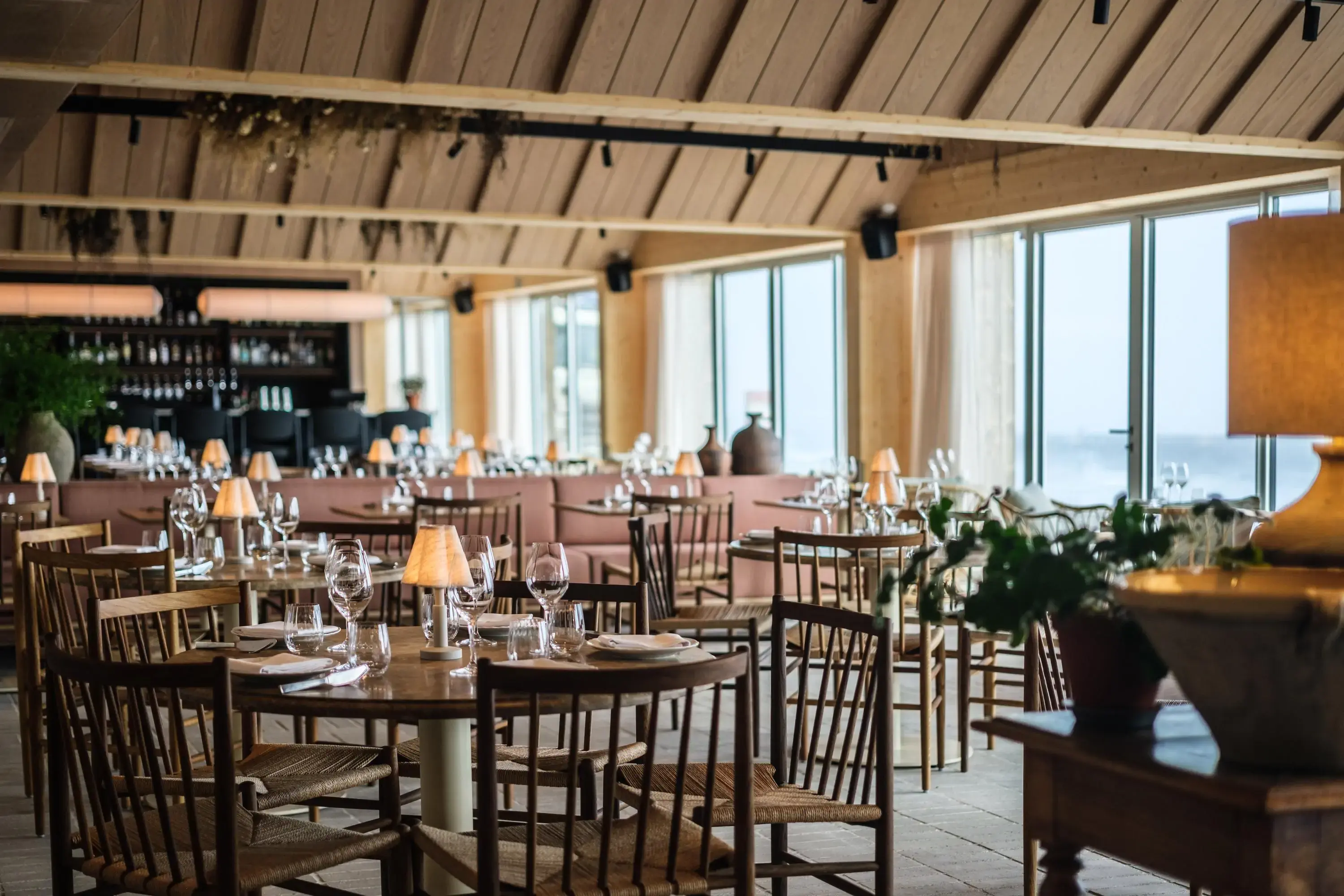 A restaurant with tables set and large windows