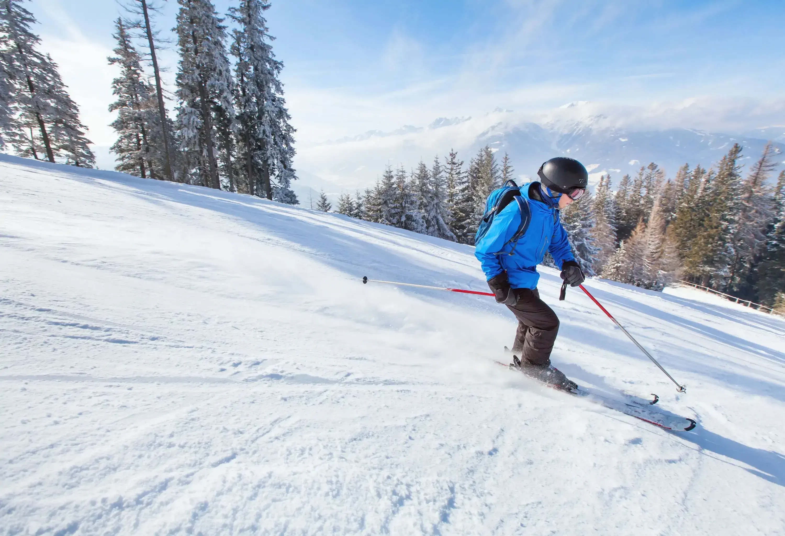 A skier descending a mountain slope while using ski poles for support.