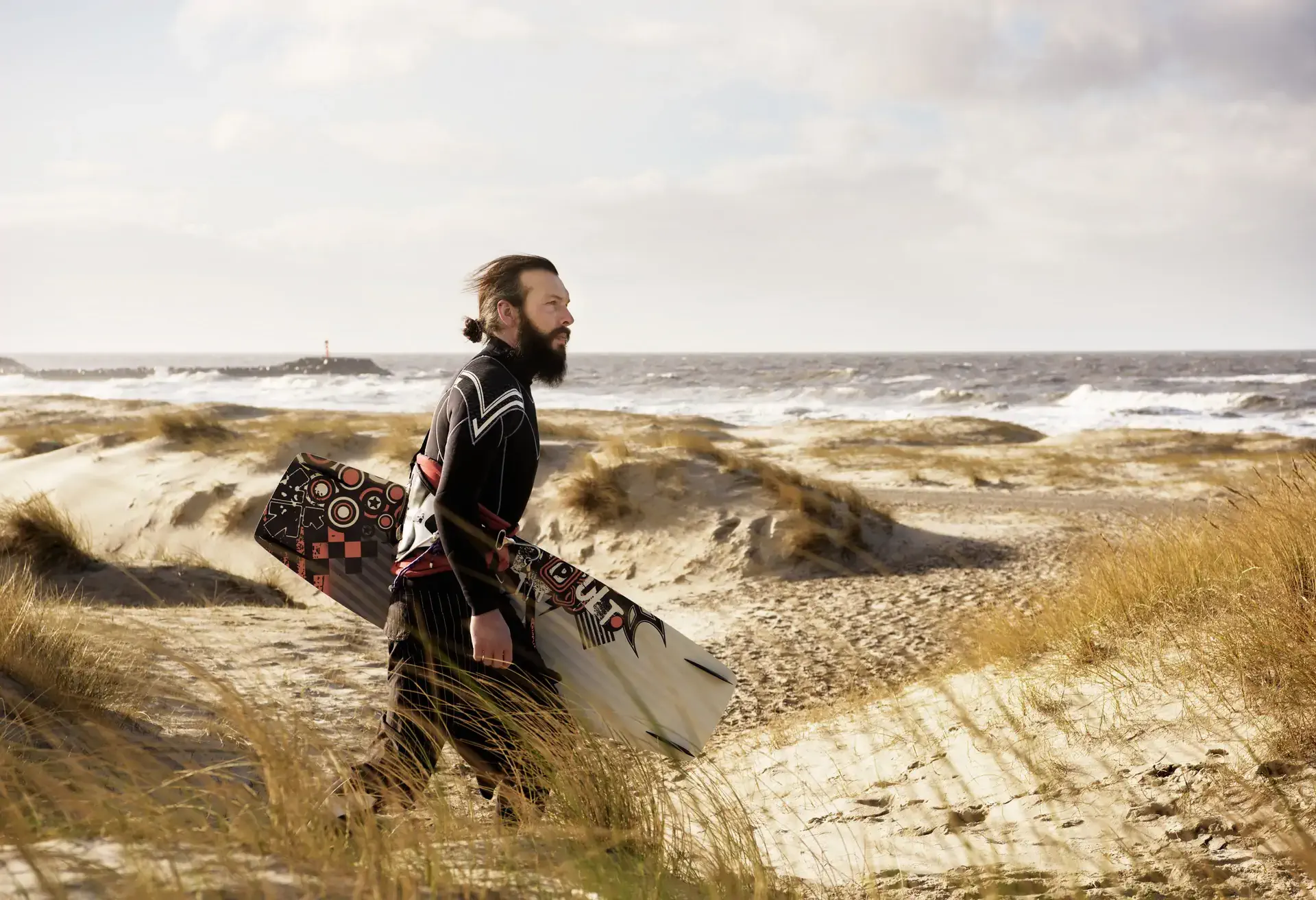Man with kitesurf board walking on beach