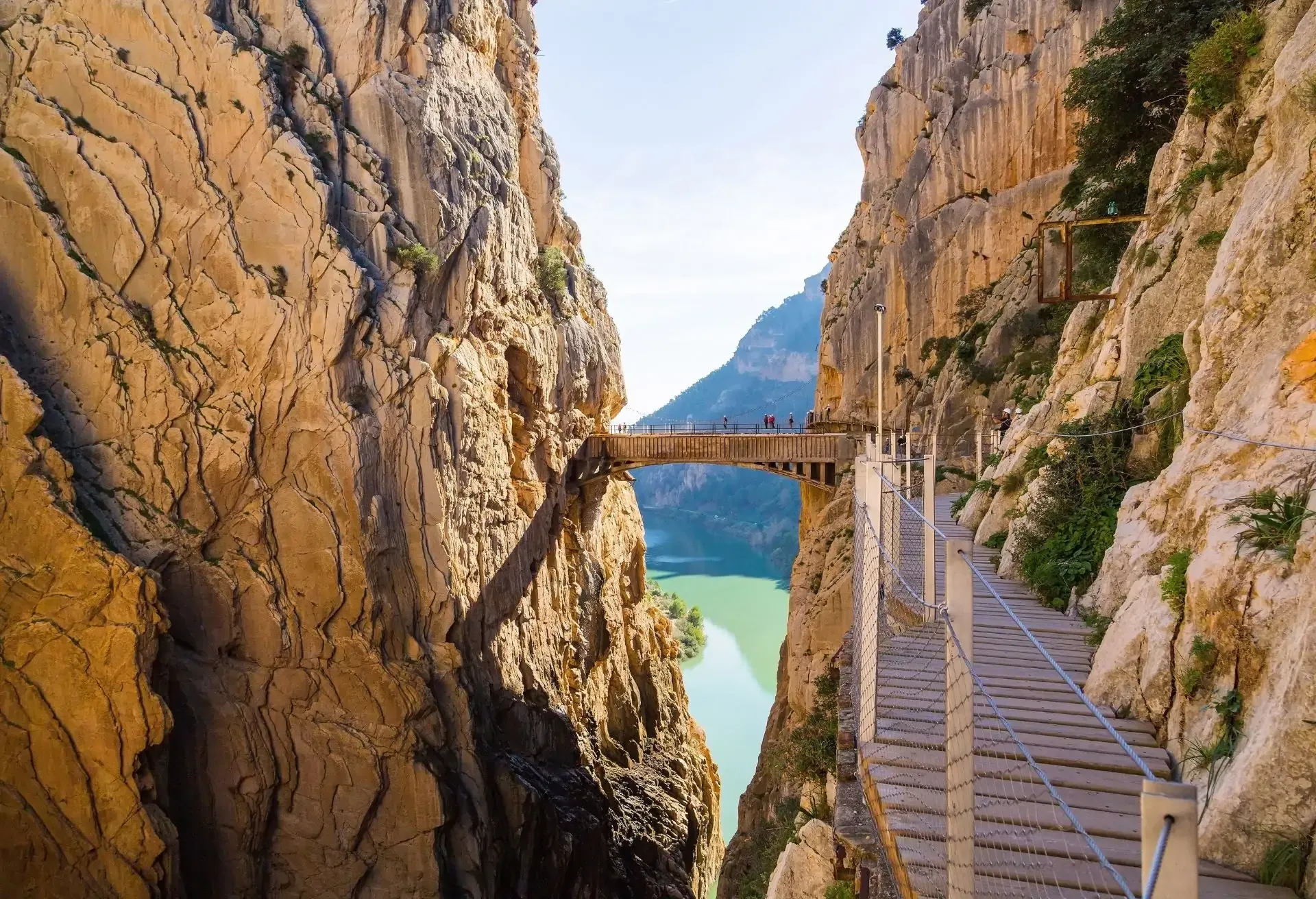 Scenic walkway suspended between steep cliffs with views of a turquoise river below.