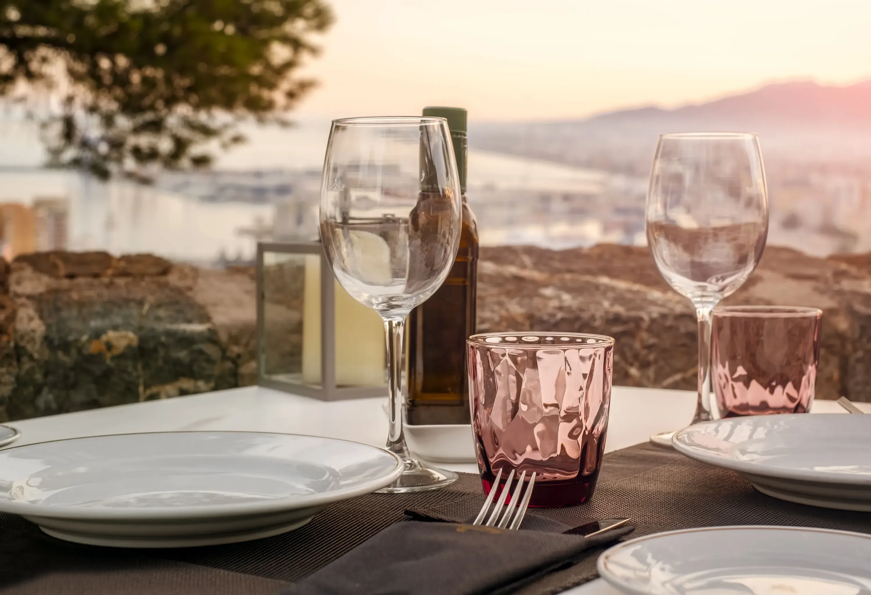 A table with a bottle of drink, wine glasses, and plates.